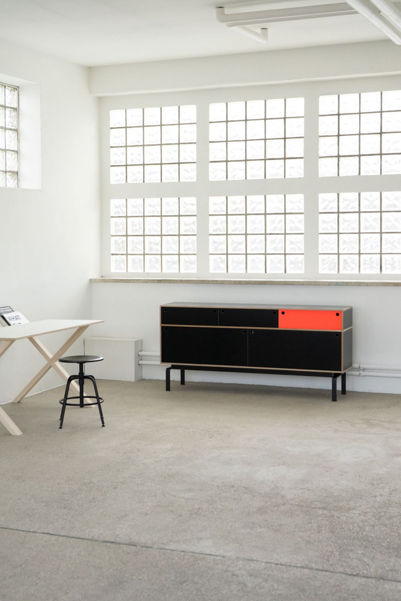 Egal Sideboard von Nils Holger Moormann, schwarz mit rotem Element, im minimalistischen Raum.