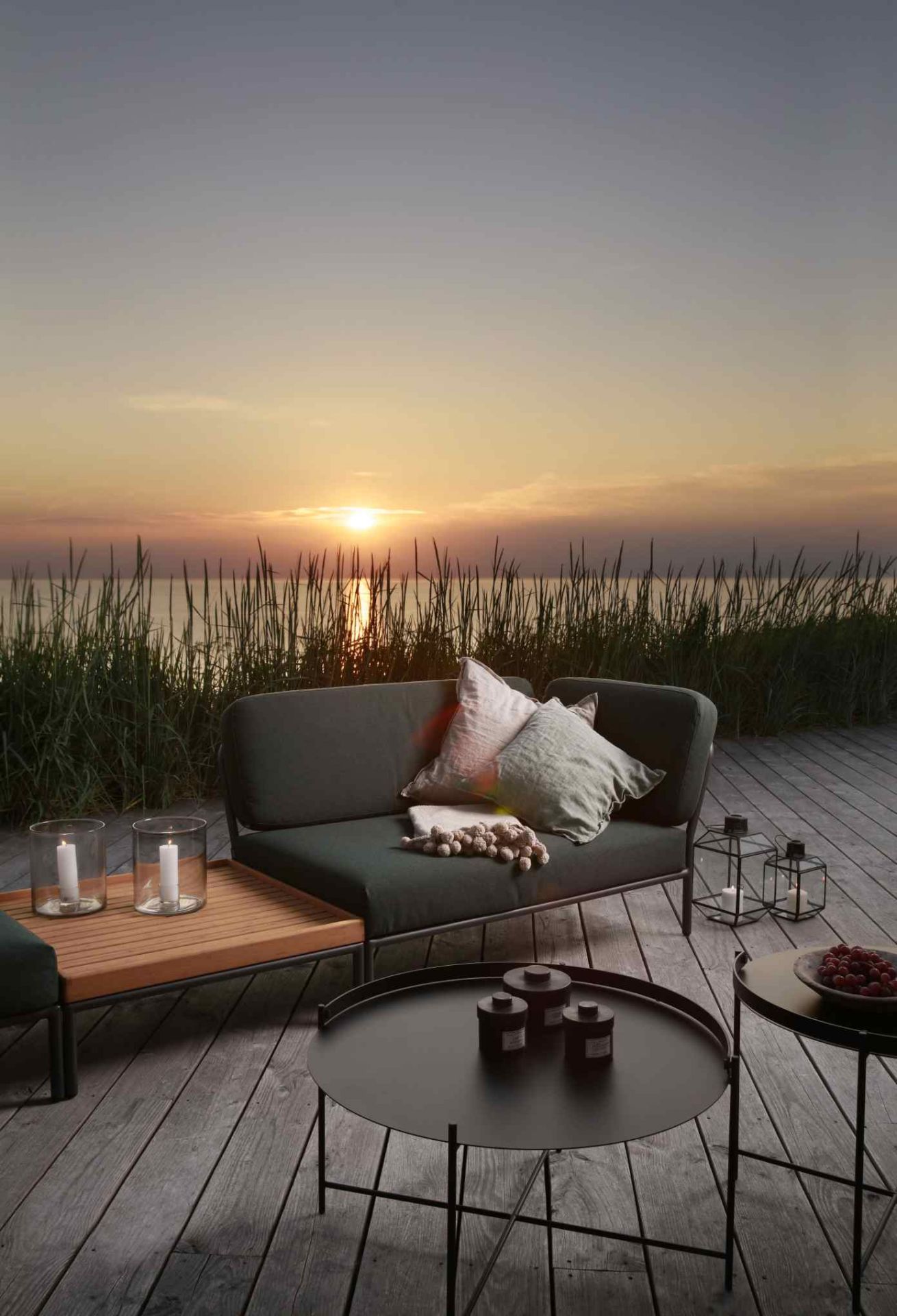 Level Sofa Outdoor von Houe auf Holzterrasse mit Meerblick bei Sonnenuntergang. Outdoor Sofa mit Kissen.