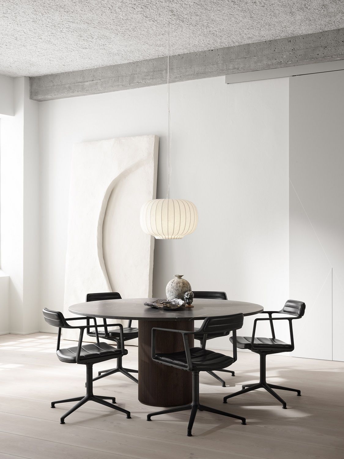 Runder Cabin Tisch von Vipp in dunkler Eiche mit schwarzen Stühlen in modernem Ambiente.