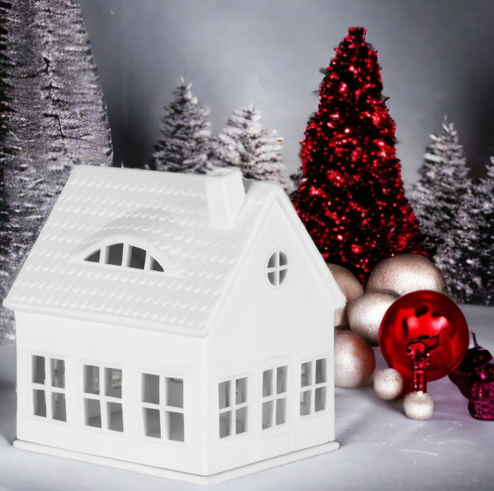 Weißes Räder Lichthaus Gaubenhaus vor weihnachtlicher Dekoration mit Bäumen und Kugeln.