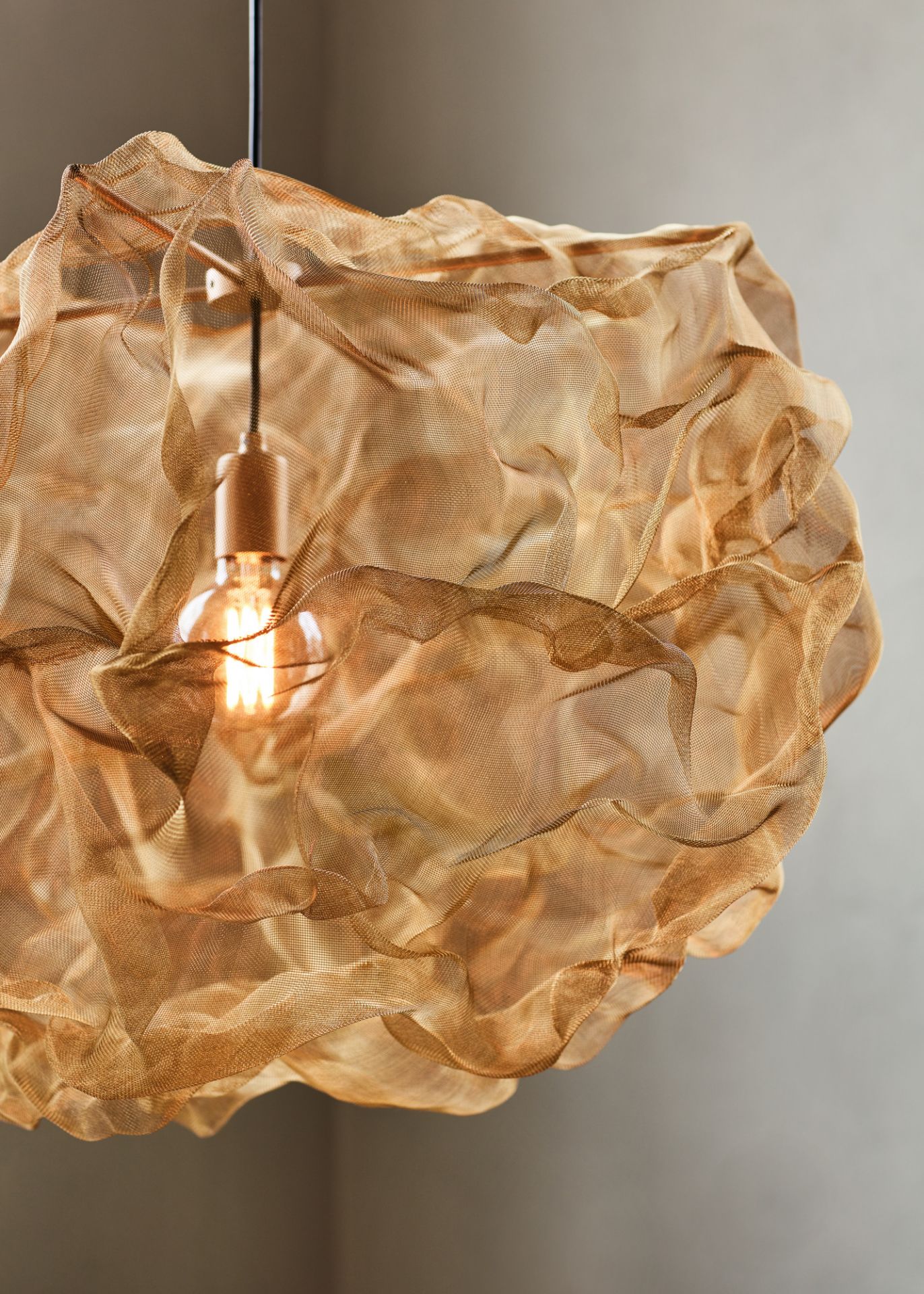 Nahaufnahme der Northern Heat Pendelleuchte mit goldfarbenem, gewebtem Lampenschirm und warmem Licht.