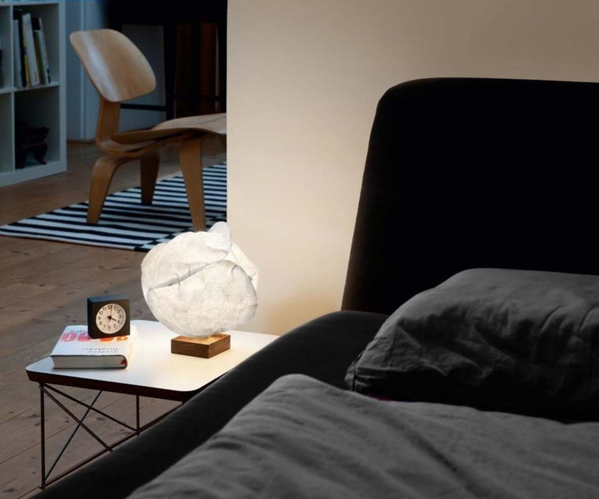 Babycloud Tischleuchte Belux auf Nachttisch neben Bett, sanftes Licht für Schlafzimmer.