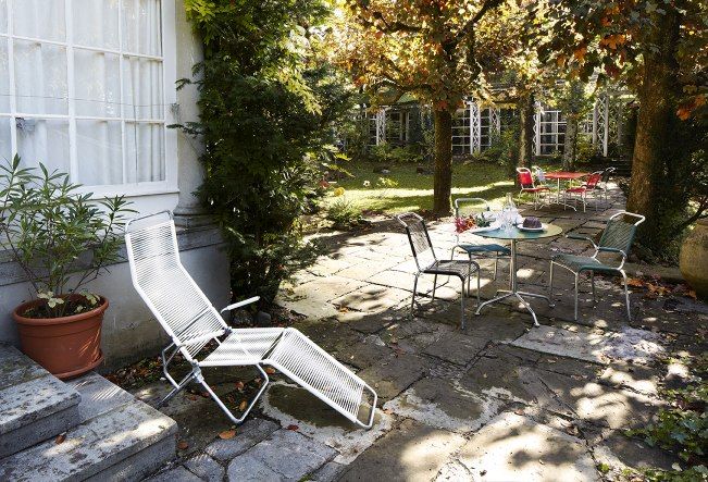 Altorfer Sessel Outdoor Embru Graphitschwarz im Garten, mit weiteren Gartenmöbeln und üppiger Bepflanzung.