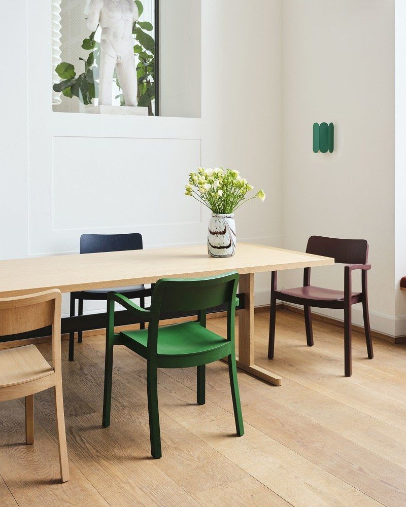 Passerelle Tisch von Hay, Esstisch aus Holz in hellem Farbton mit farbigen Stühlen.
