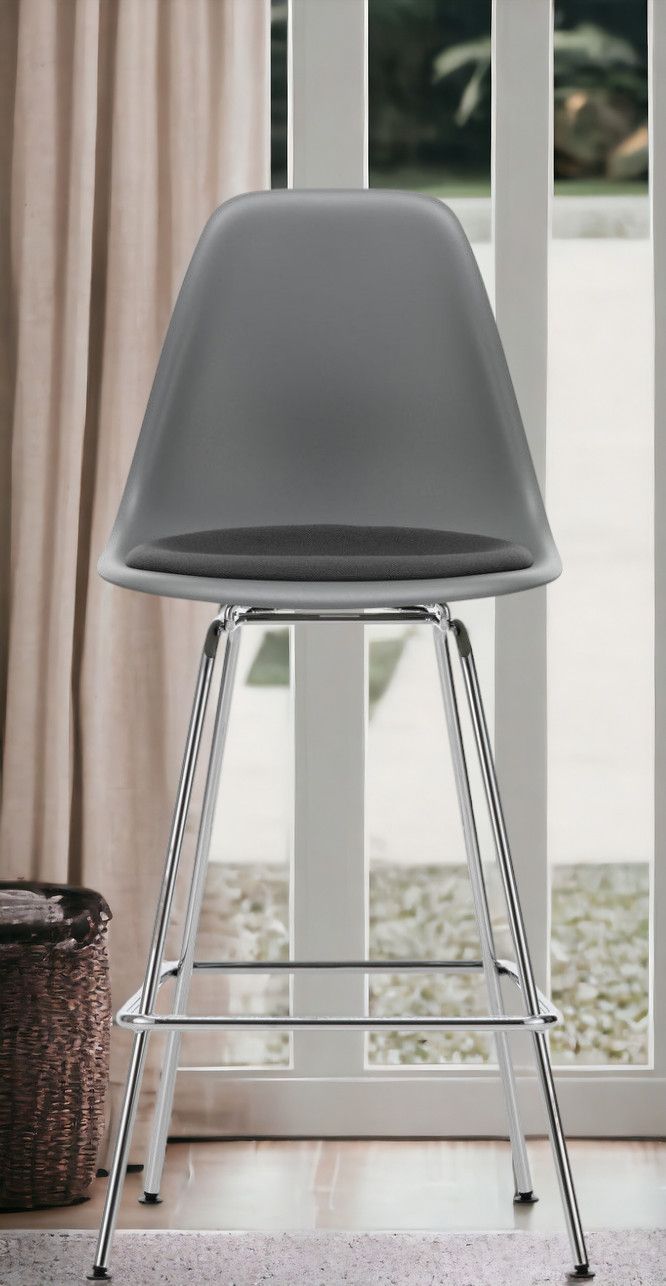 Grauer Eames Plastic Bar Stool Barhocker von Vitra mit Sitzpolster und verchromtem Gestell.