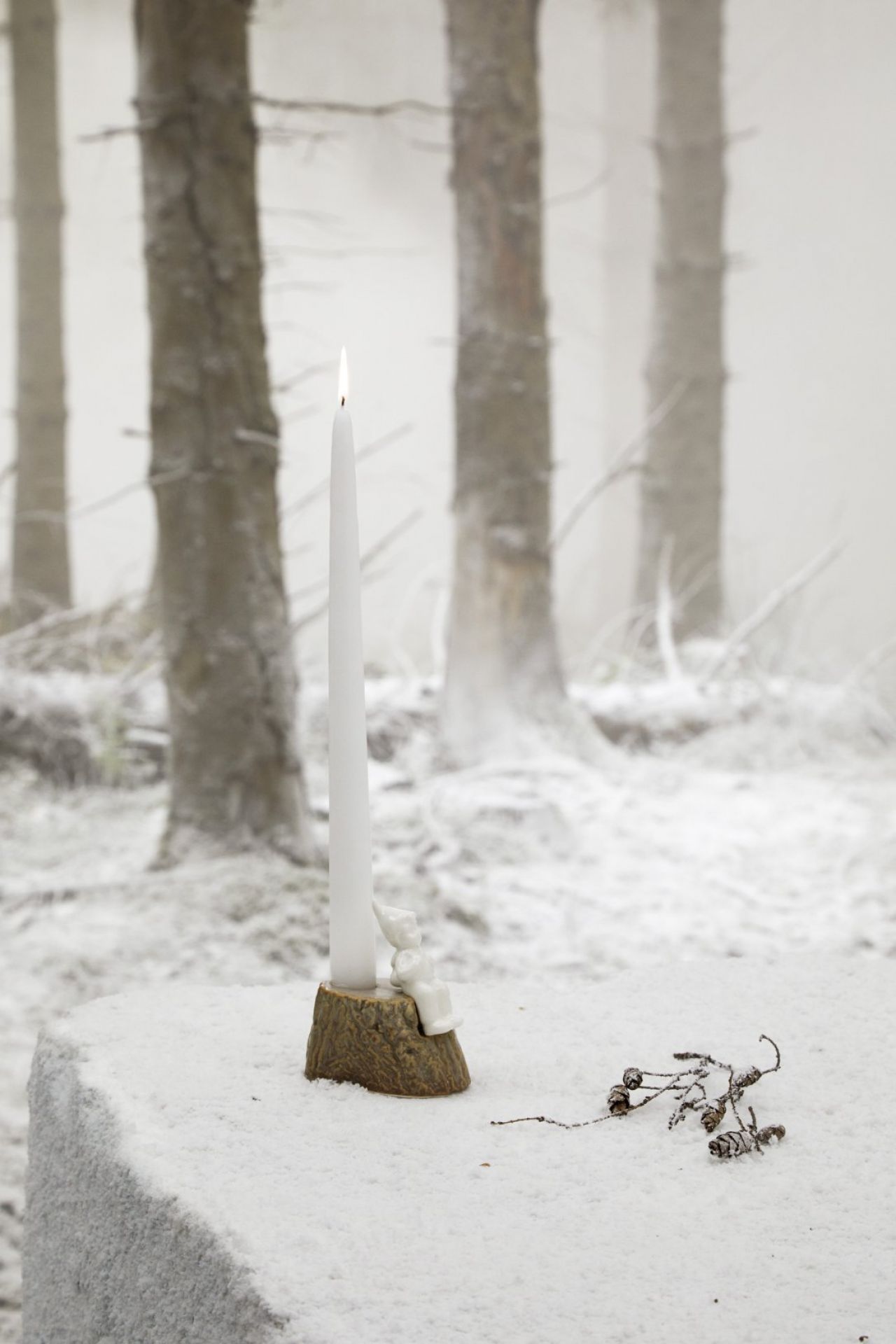 Kähler Christmas Tales Kerzenhalter mit brennender Kerze vor verschneitem Wald. Weihnachtliche Dekoration.