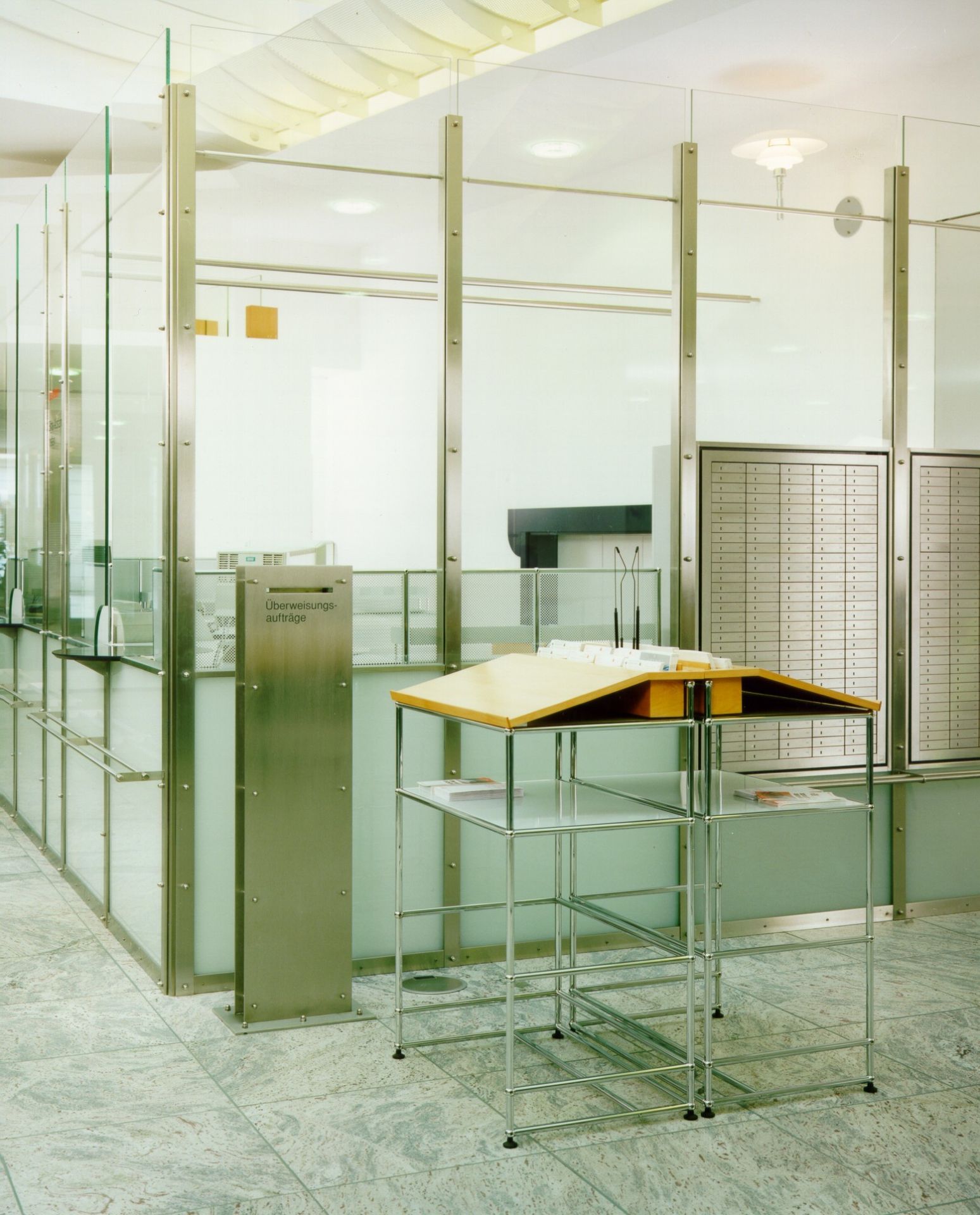 USM Haller Stehpult mit Holzplatte und Chromgestell in einem modernen Bürogebäude, ideal für ergonomisches Arbeiten.