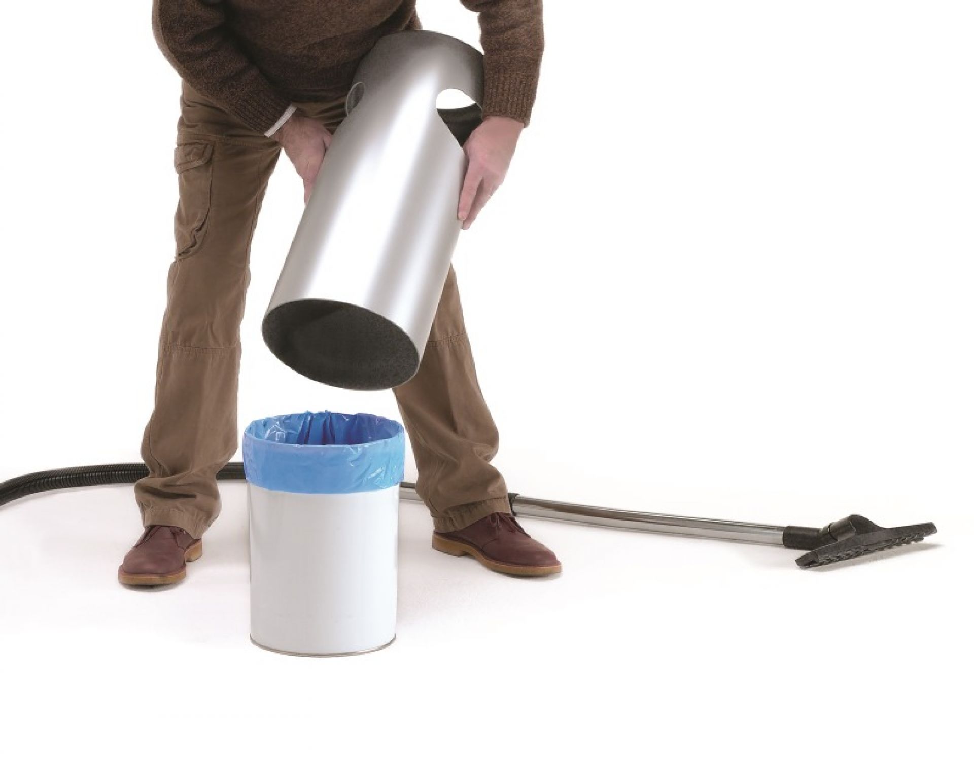 Mann leert Rexite Birillo Plus Papierkorb. Silberner Behälter über weißem Eimer mit blauem Müllbeutel.