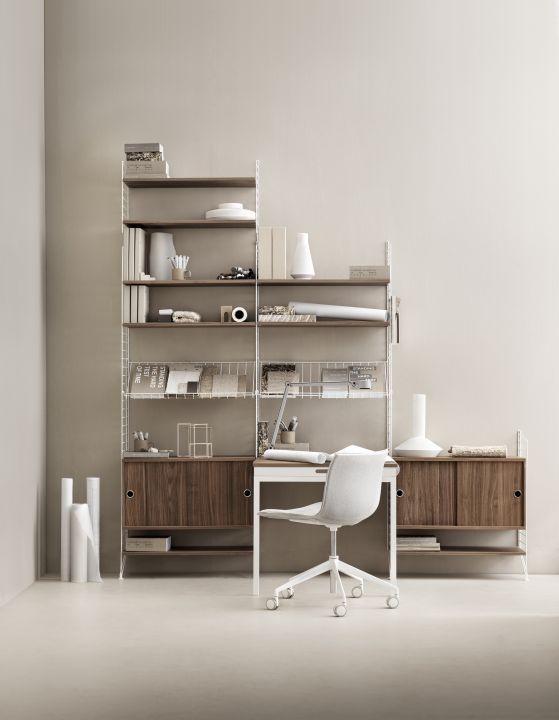 Büro mit String Regalsystem, Schreibtisch und Stuhl. Metall Zeitschriftenablage im Regal.