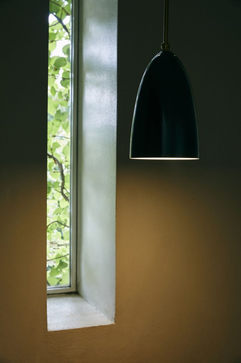 Nahaufnahme der schwarzen Gräshoppa Pendelleuchte von Gubi, die ein warmes Licht in einem Raum verbreitet.