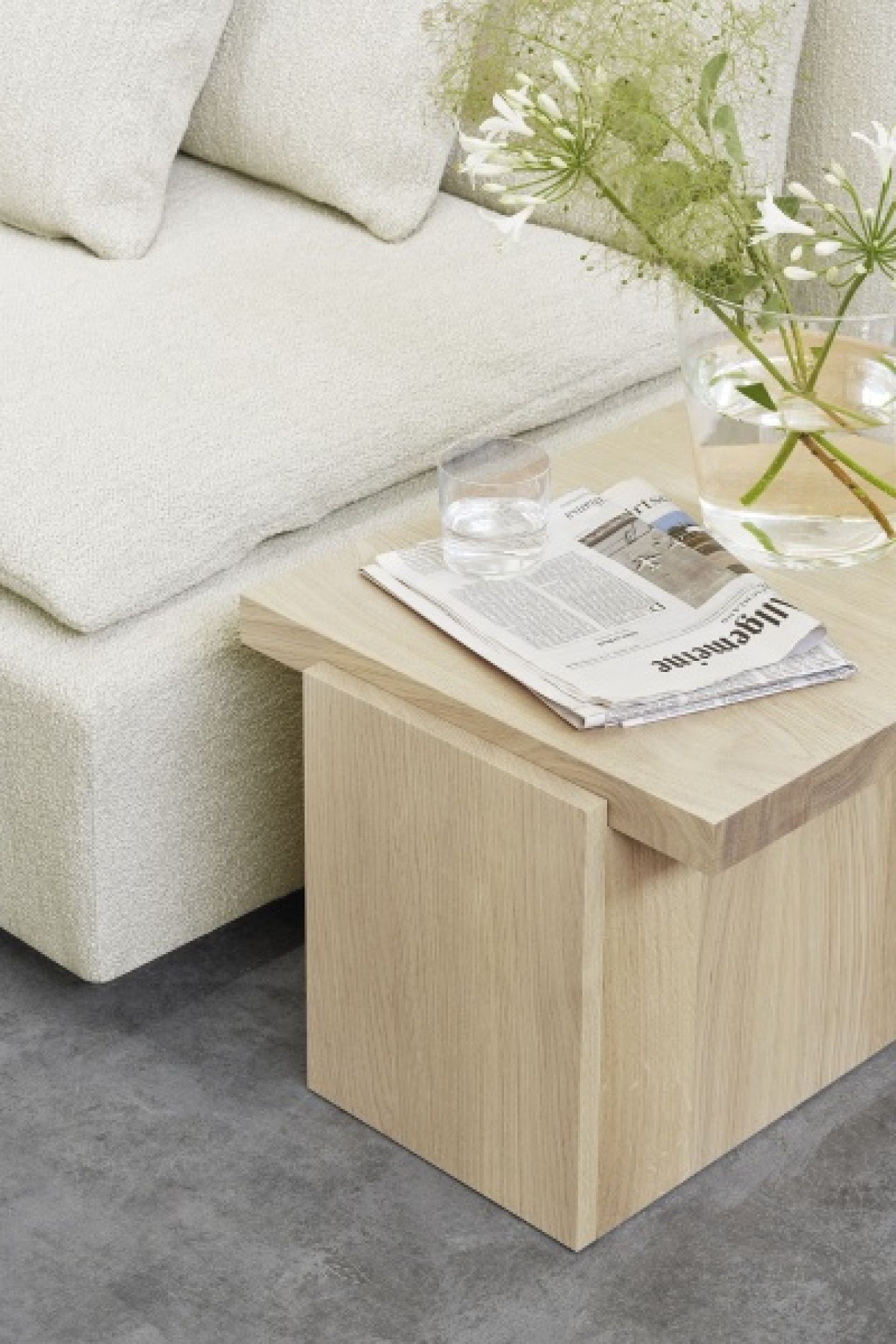 DT02 Tore Beistelltisch von e15 aus geölter Eiche, neben einem Sofa mit Zeitung.