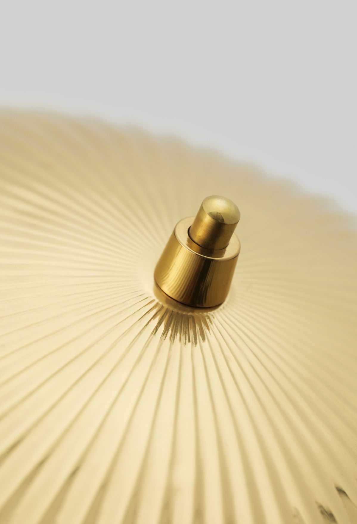 Detailaufnahme der goldenen Gubi 5321 Tischleuchte mit geriffeltem Lampenschirm und Schalter.