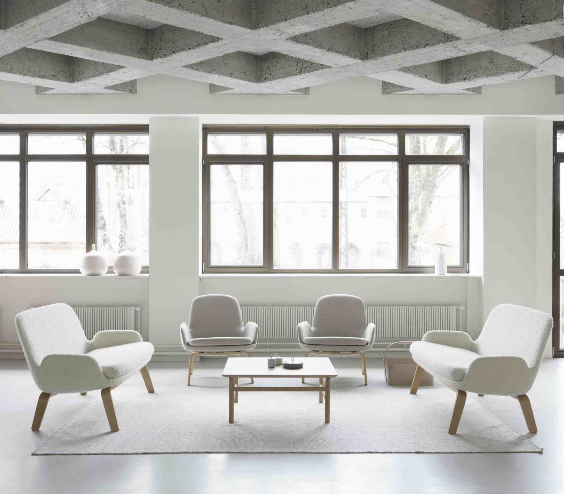 Helles Wohnzimmer mit Grow Table Couchtisch von Normann Copenhagen und Sesseln auf einem Teppich.