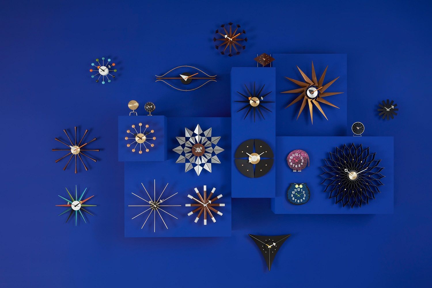 Vielfalt an Vitra Wanduhren, darunter die Nelson Flock of Butterflies Uhr, auf blauem Hintergrund.
