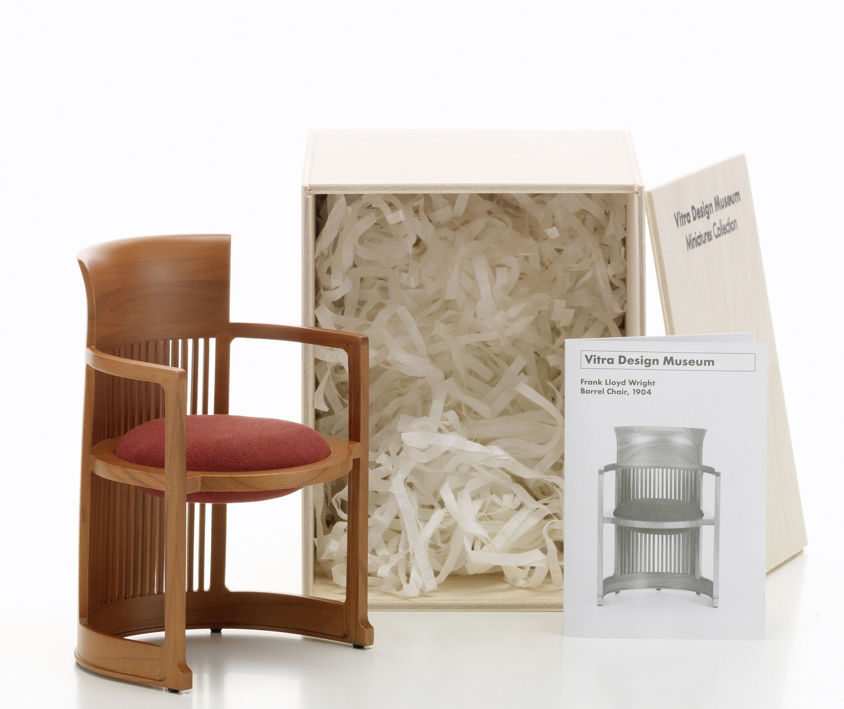 Detailaufnahme: Barrel Chair Miniatur Stuhl von Vitra, Holzstuhl mit rotem Sitzkissen, Sammlerstück.