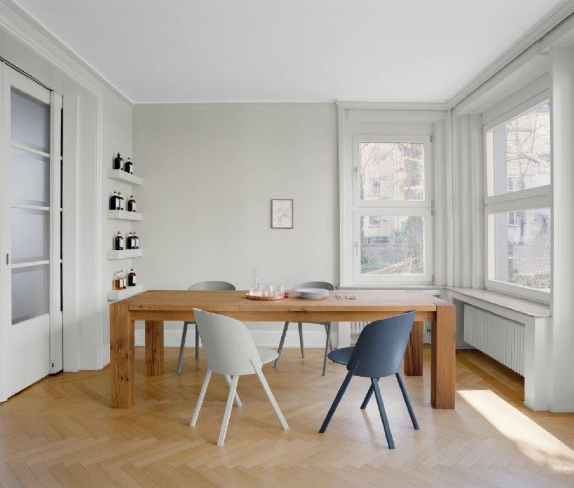 Esszimmer mit Holztisch und CH05 Stühlen von e15 in Weiß, Grau und Blau.