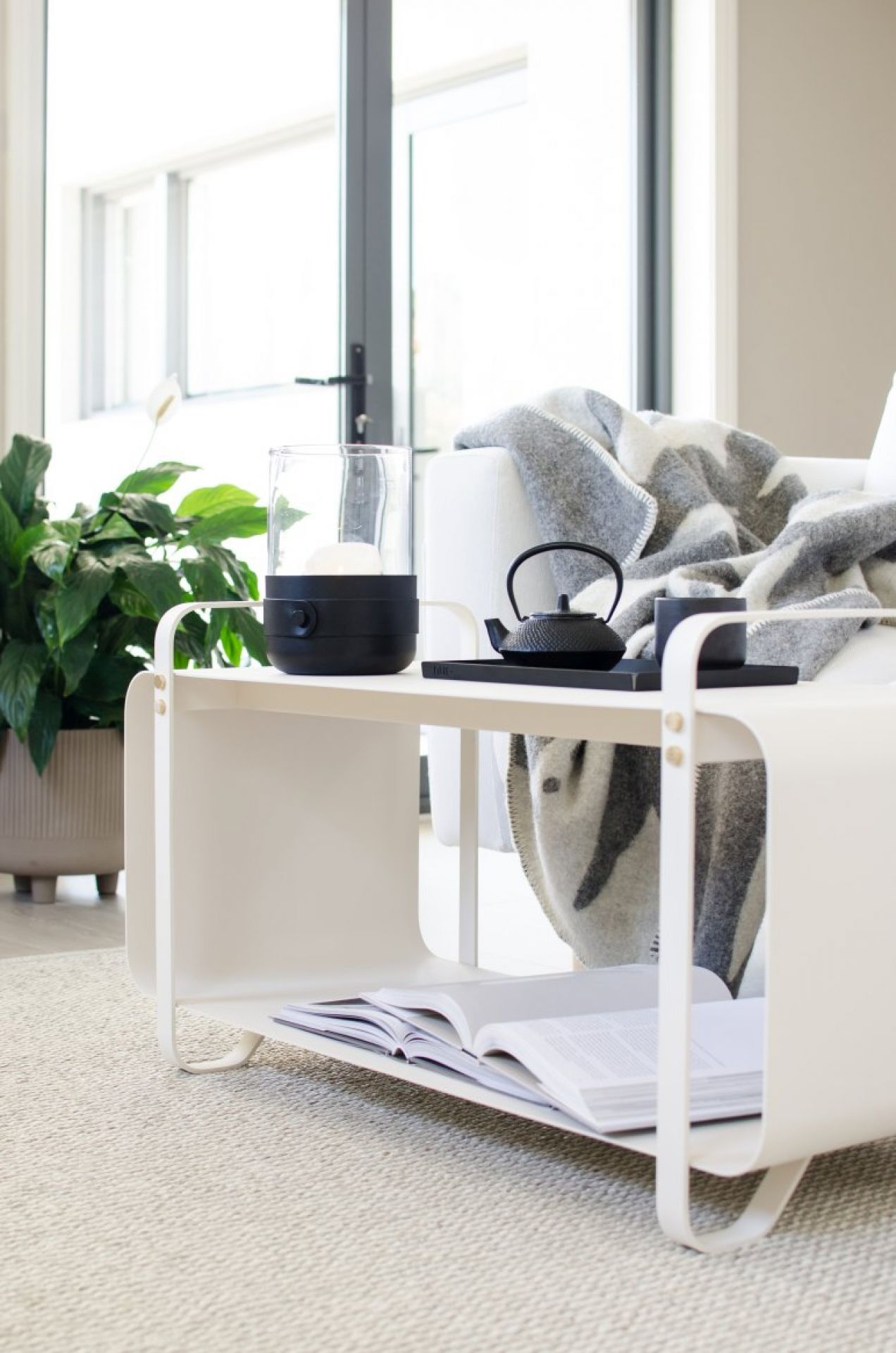 Detailaufnahme des Mono Kunststoffteppichs von Pappelina, der in einem hellen Wohnzimmer liegt. Teppichboden, Möbel und Dekoration.