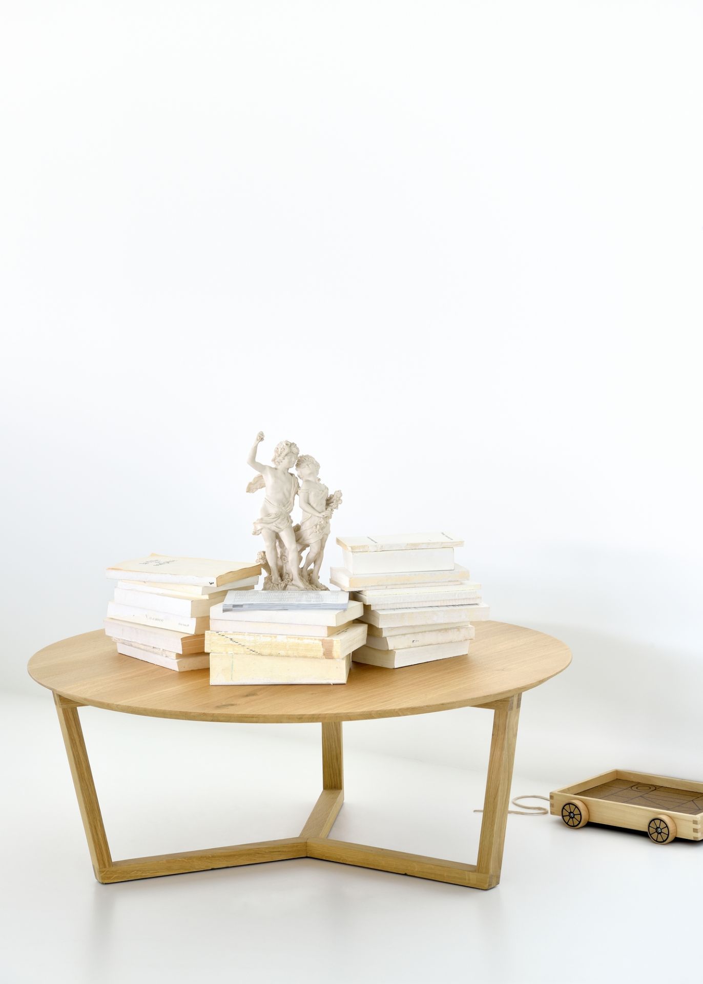 Ethnicraft Couchtisch Tripod aus Eiche mit Büchern und einer Skulptur dekoriert, minimalistisches Design.