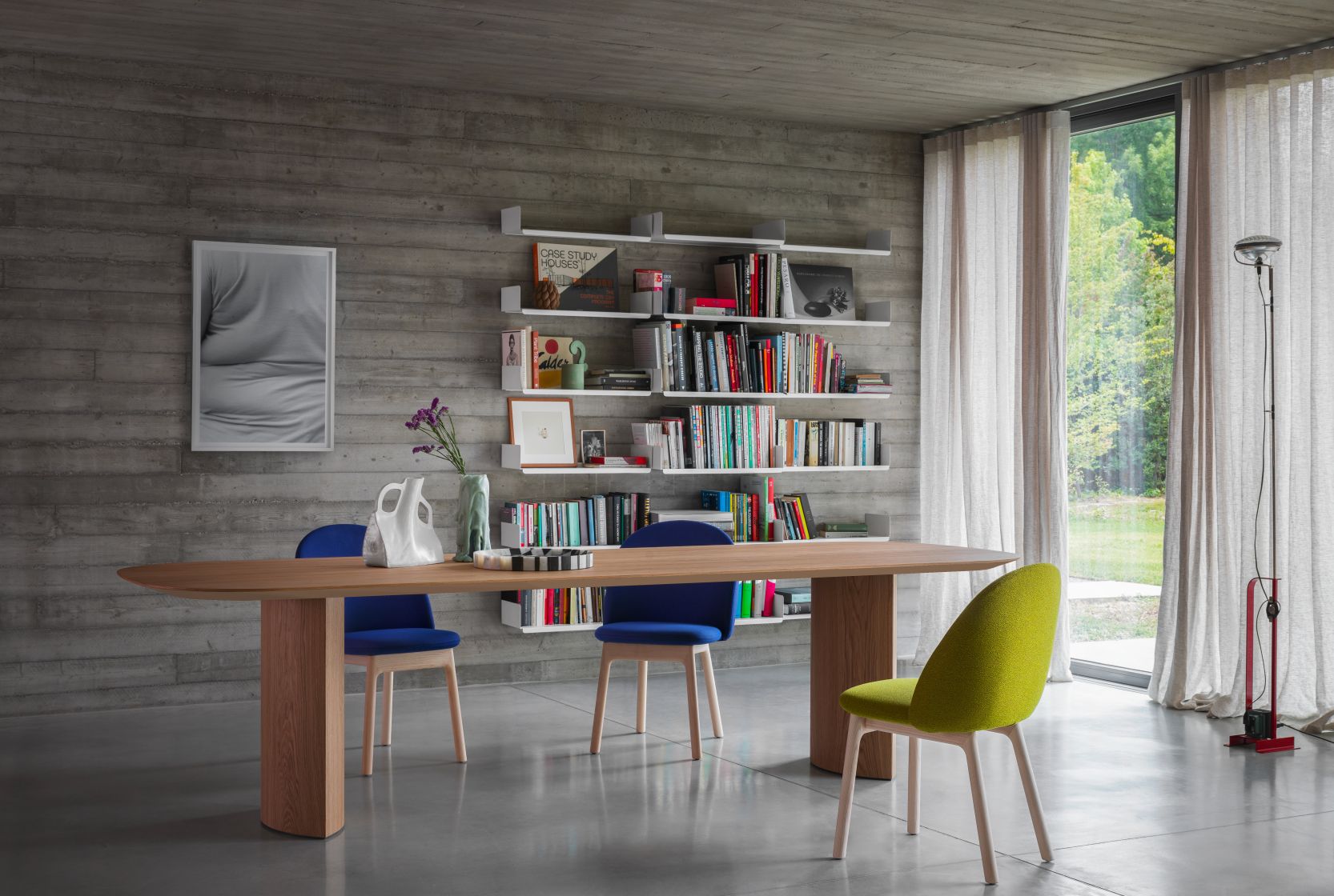 Plauto Esstisch von Miniforms aus Holz mit blauen und grünem Stuhl vor Bücherregal.