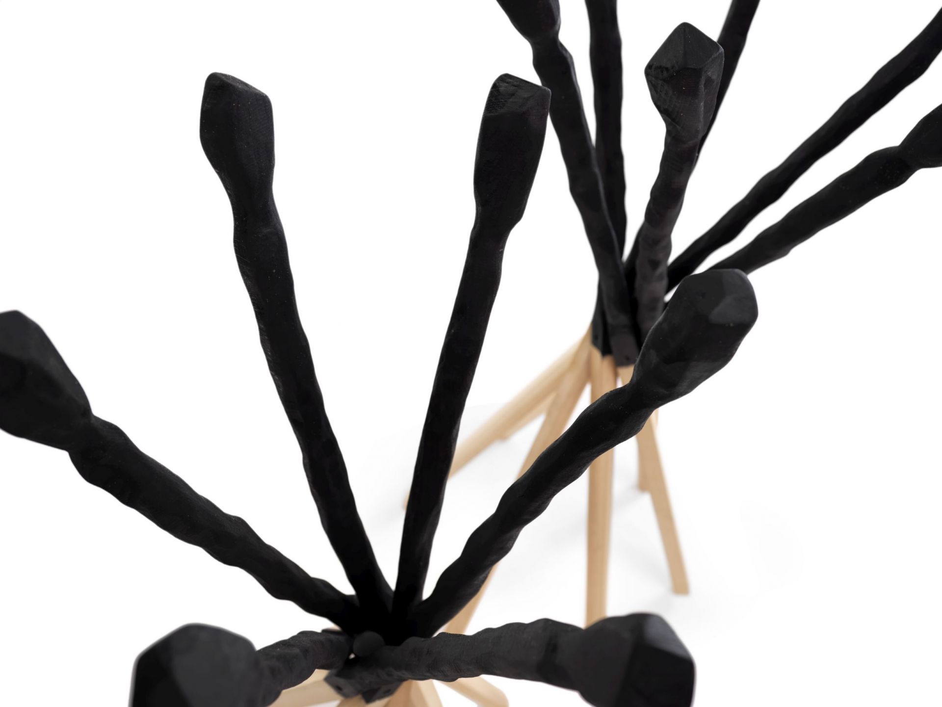 Detailaufnahme des Match Kleiderständers von Mogg mit schwarzen Ästen und hellem Holzfuß.