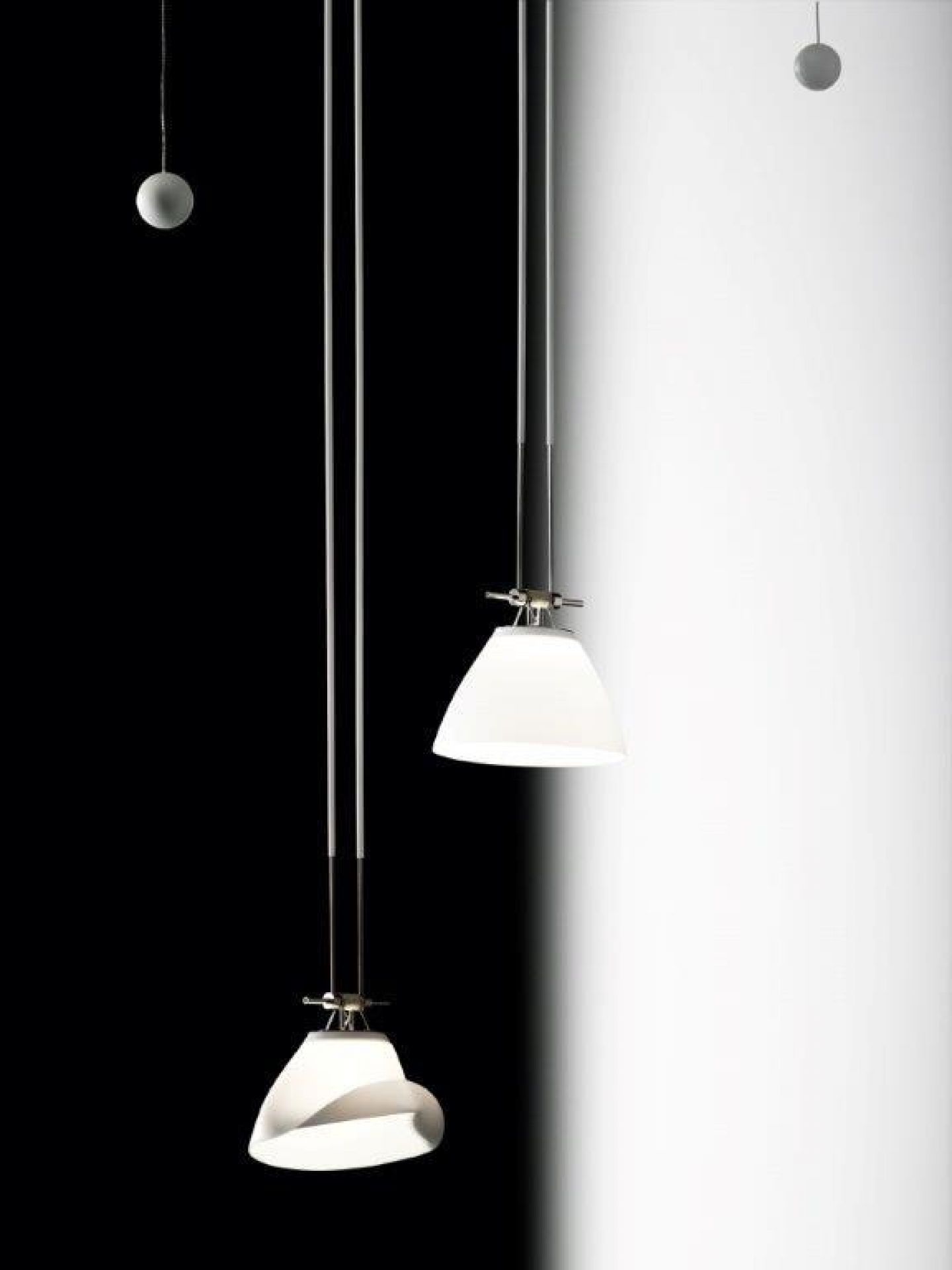 YAYAHO Lichtsystem von Ingo Maurer: Zwei Hängelampen mit weißen Schirmen vor Schwarz-Weiß-Hintergrund.