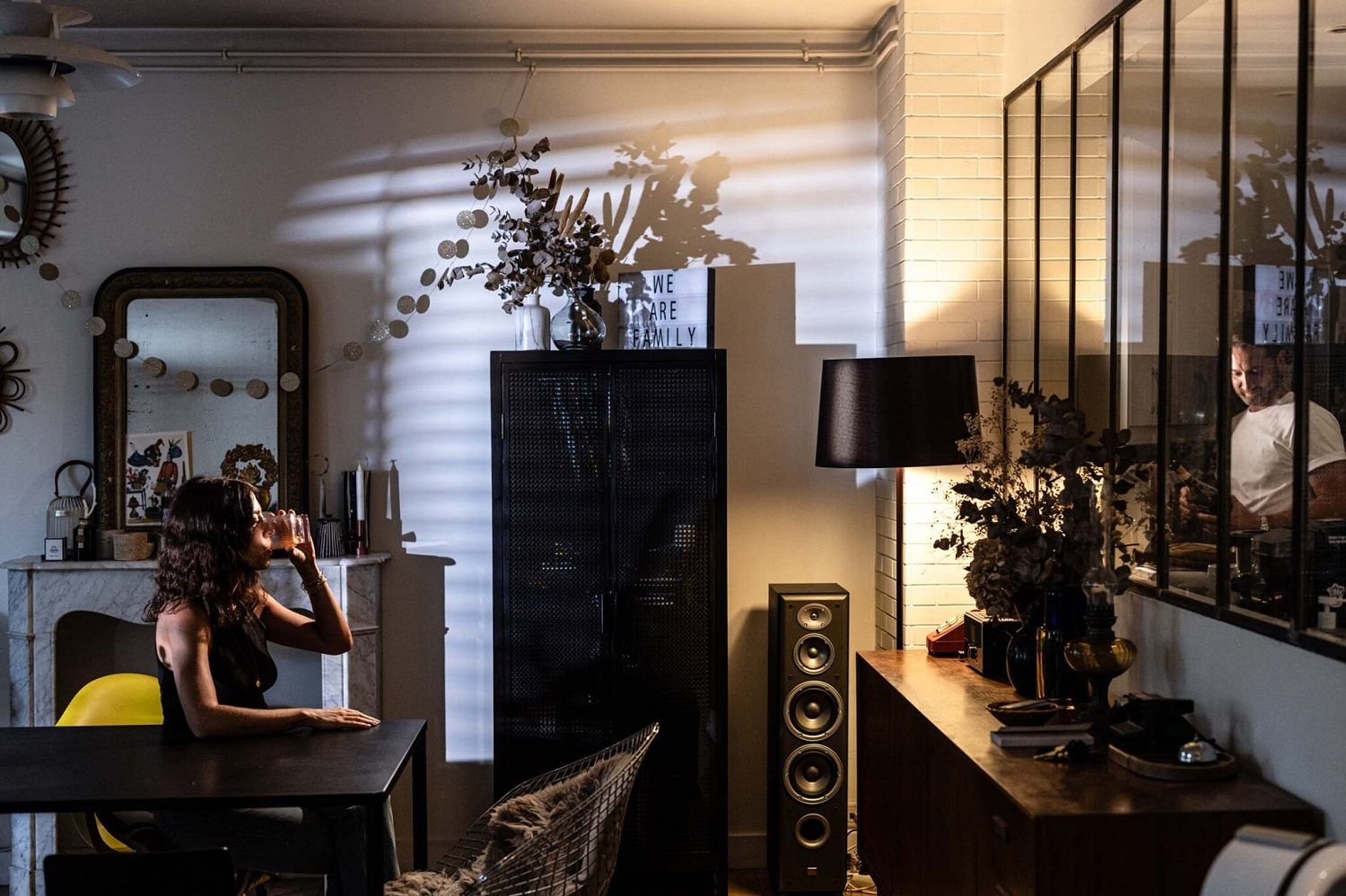 Moderne Twiggy Lettura Stehleuchte von Foscarini in stilvollem Wohnzimmerambiente mit Frau am Tisch und gedämpftem Licht.