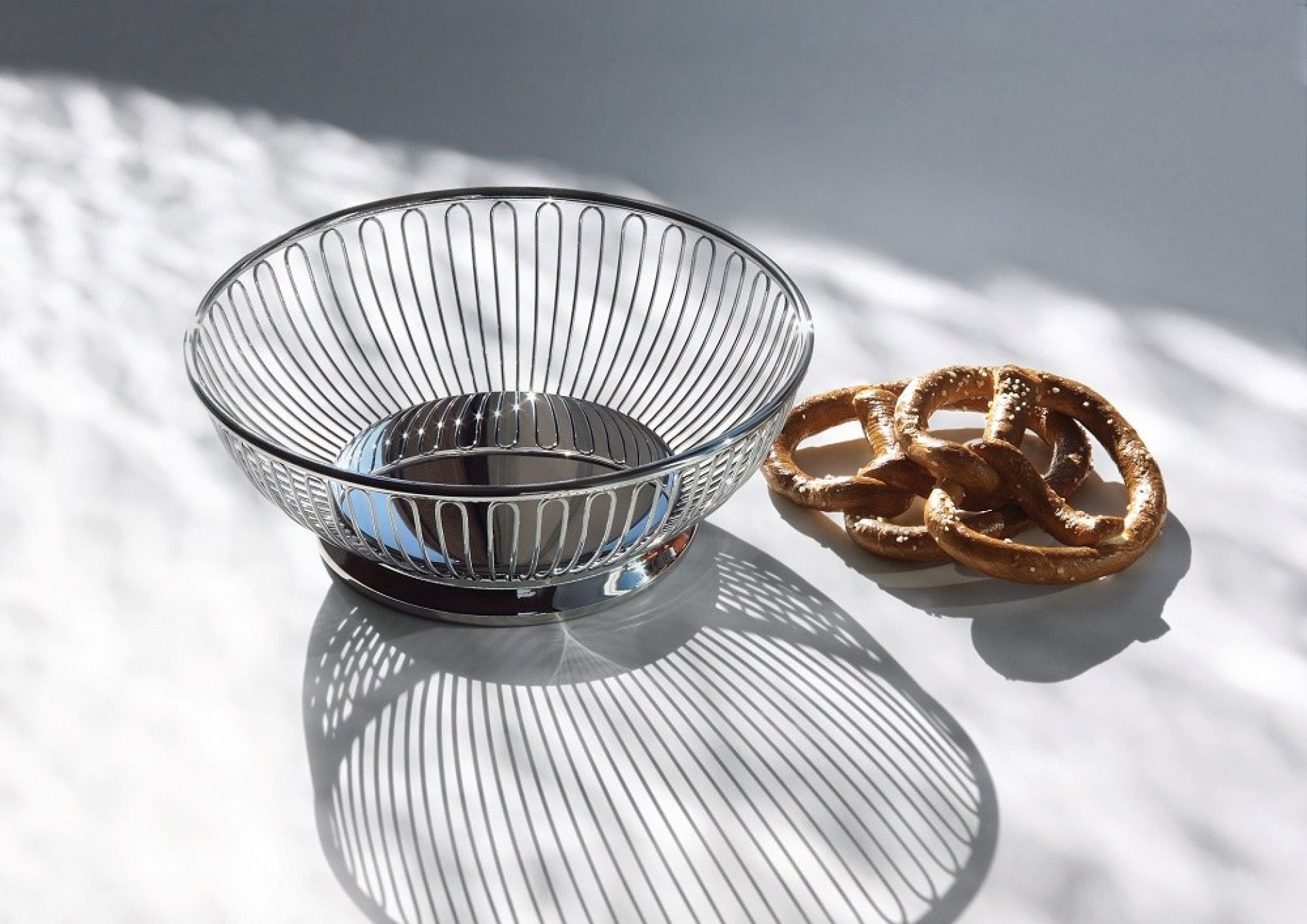 Alessi Drahtkorb 826/24 aus glänzendem Edelstahl mit Brezeln, ideal als Obstkorb oder Brotkorb.