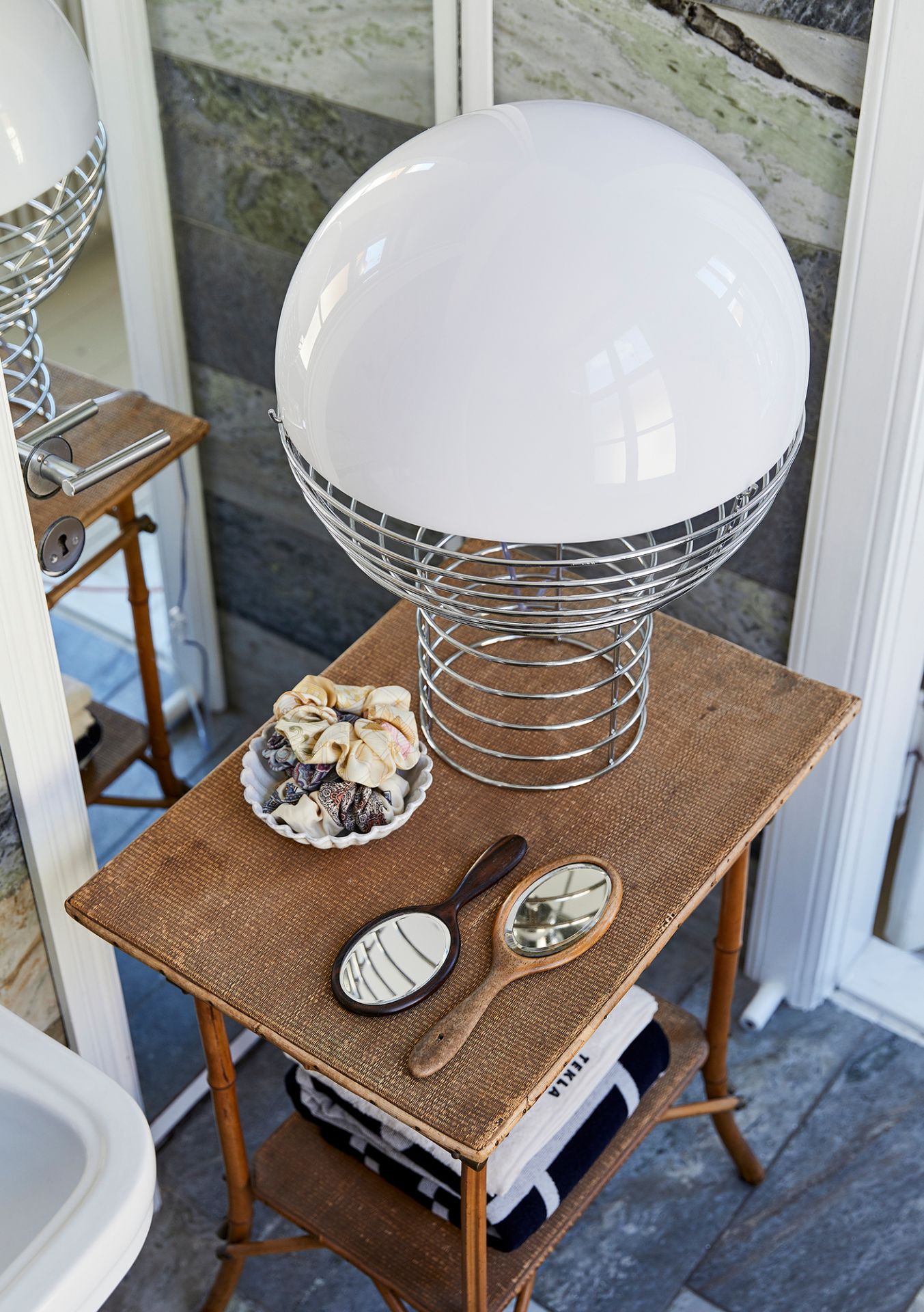 Verpan Wire Large Tischleuchte mit weißem Lampenschirm auf einem Beistelltisch im Badezimmer.