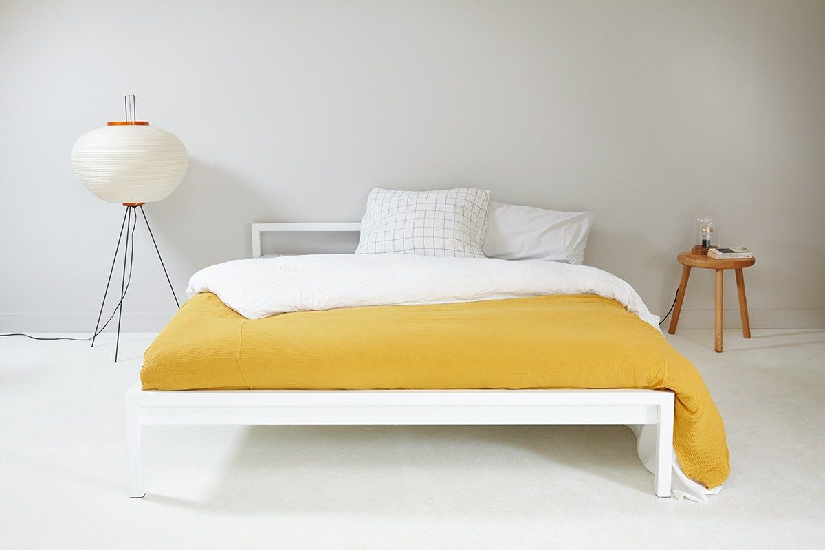Weißes Pure Bett Stahl von Hans Hansen (200x200 cm) mit gelber Tagesdecke.