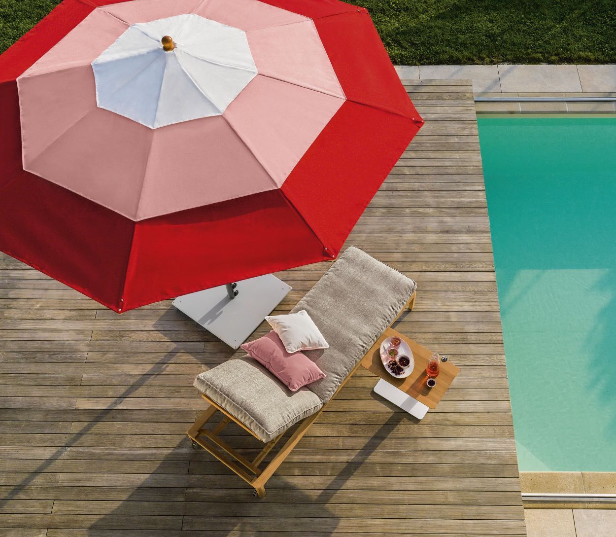 New Hampton Sonnenliege von Weishäupl am Pool mit Sonnenschirm und Getränken.