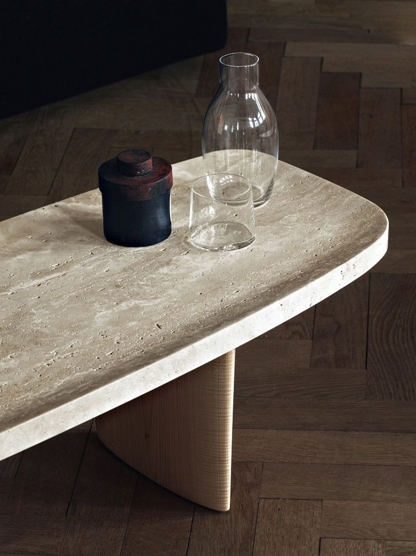 Classicon Beistelltisch Matéria Long table aus Travertin mit Holzfuß, darauf Glasvase und Becher.