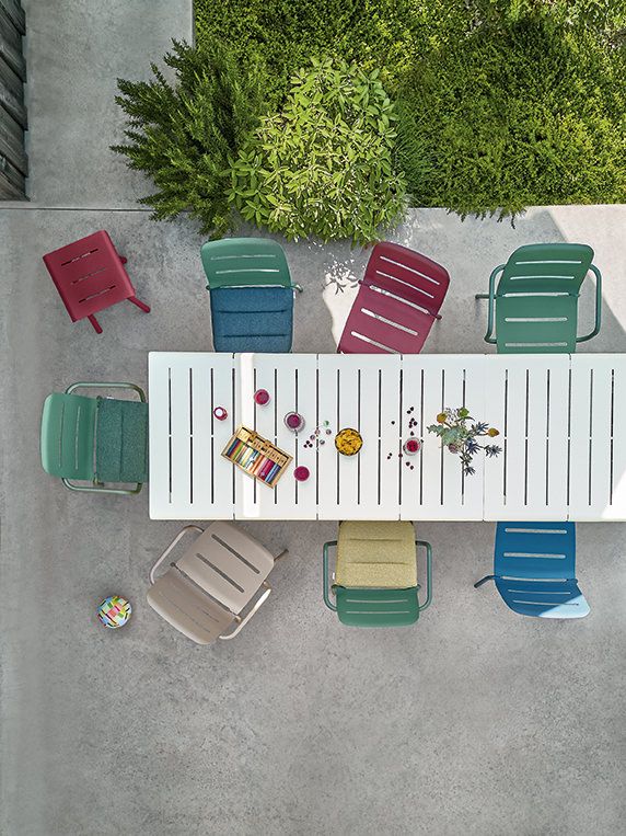 Draufsicht auf Esstisch mit farbenfrohen Weishäupl Vapio Stühlen und Hocker im Garten, ideal für Outdoor-Bereiche.