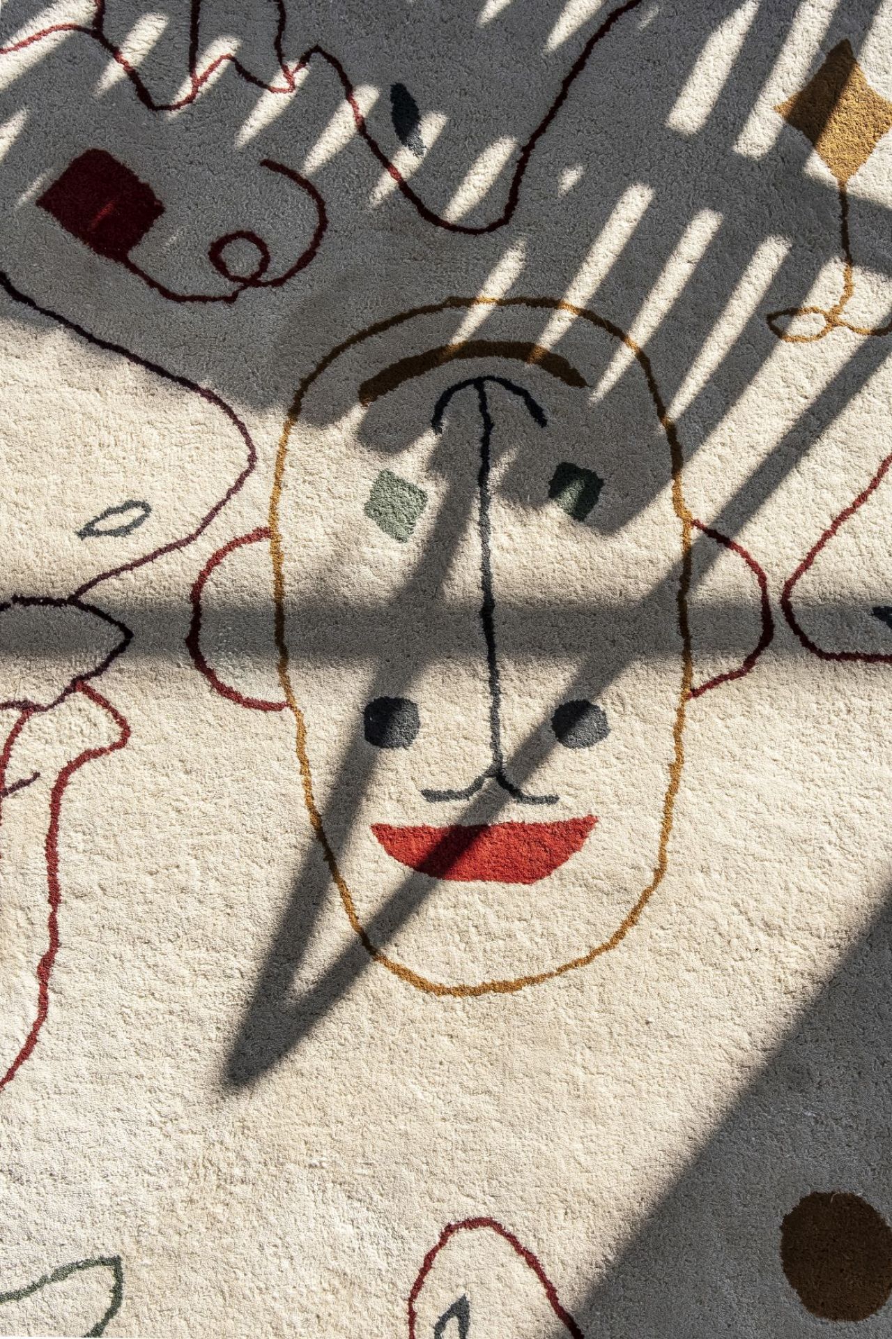 Detailaufnahme Nanimarquina Teppich: Beige Outdoor Teppich mit abstraktem Gesichtsmuster und Schatten.