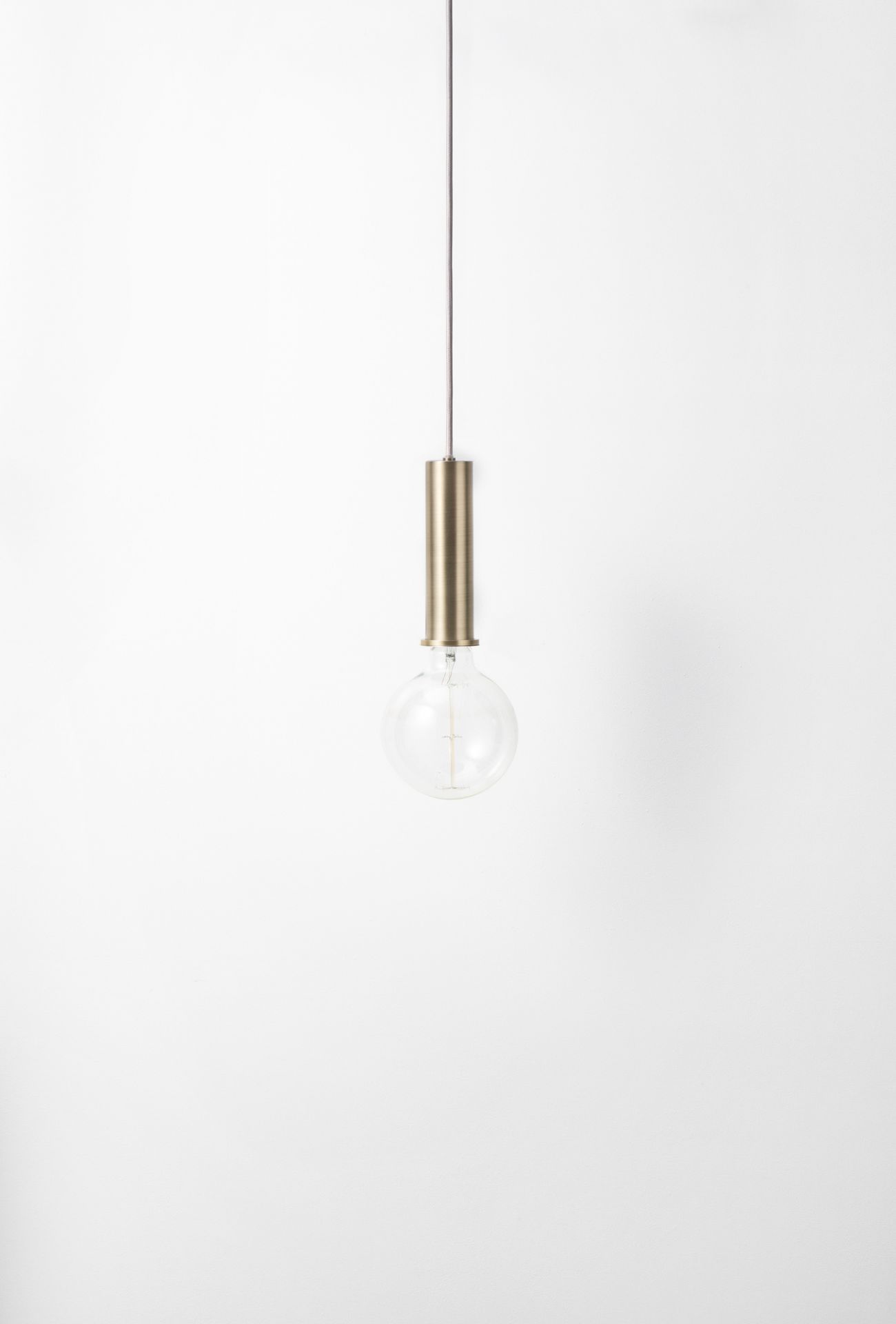 Nahaufnahme der Ferm Living Collect Pendelleuchte in hoch Messing mit Glühbirne.