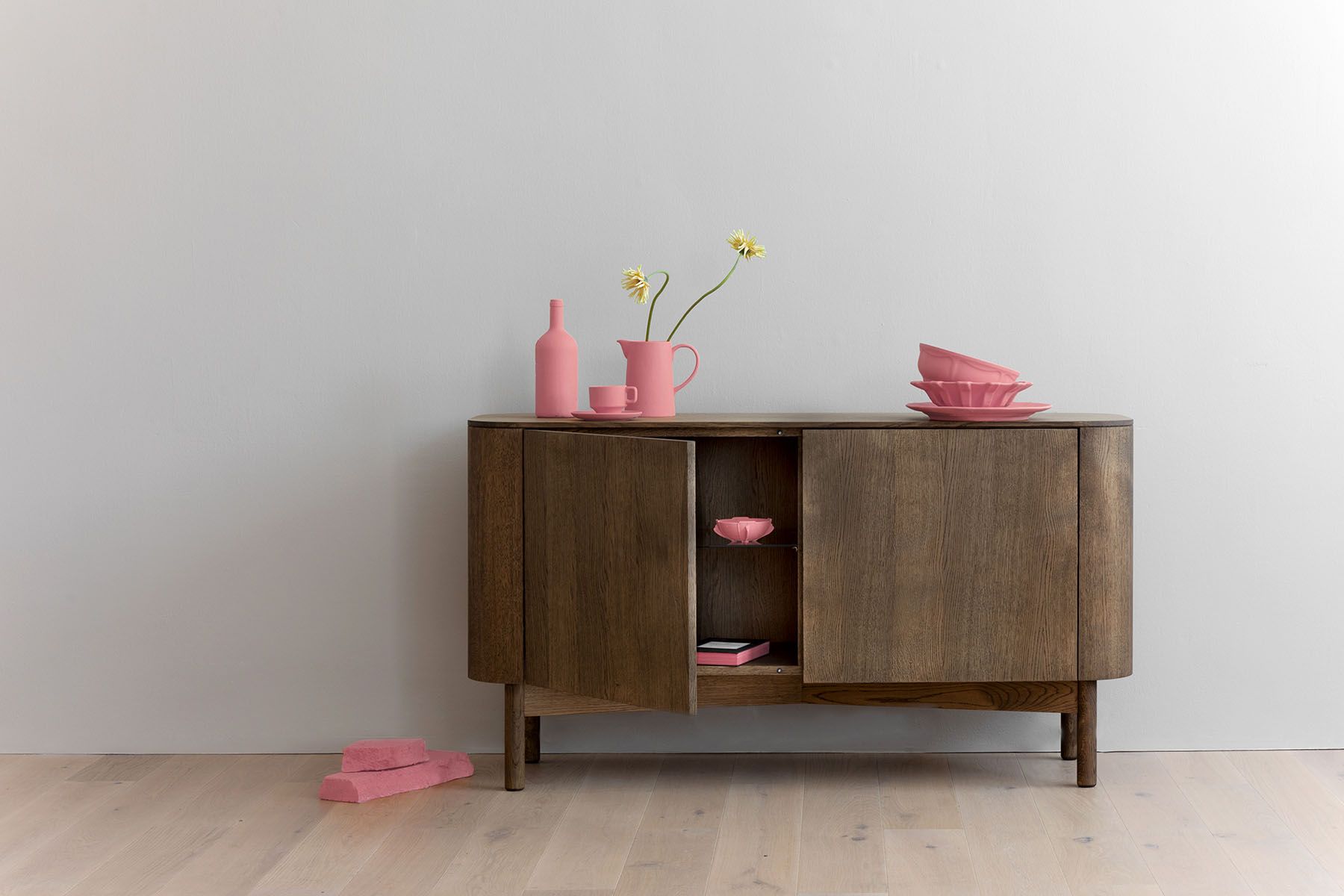 Loud Sideboard aus Eiche hell von Northern mit offener Tür und pinker Deko.