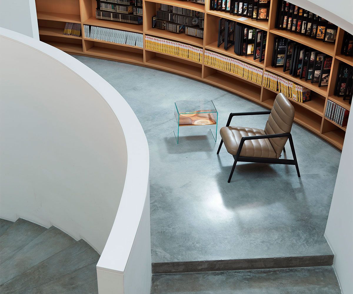 Bifronte Beistelltisch von Casamania Horm, quadratisch mit Glasplatte, neben Sessel in modernem Wohnzimmer.