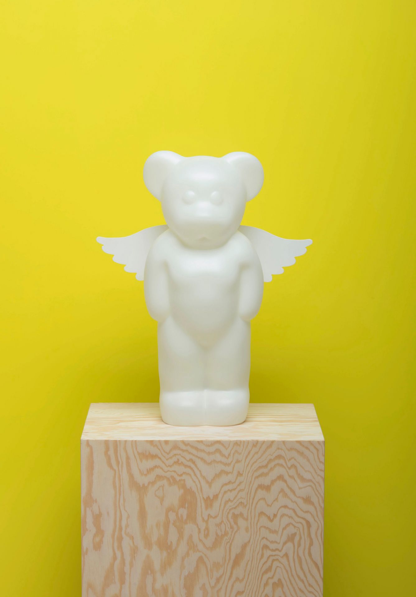 Weiße Lumibär Stehleuchte mit Flügeln auf einem Holzsockel vor gelbem Hintergrund. LED-Lampe, Kinderzimmer.