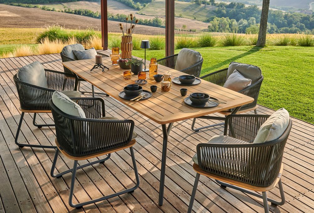 Denia Teak Esstisch von Weishäupl mit Stühlen auf Holzterrasse im Grünen. Outdoor Möbel.