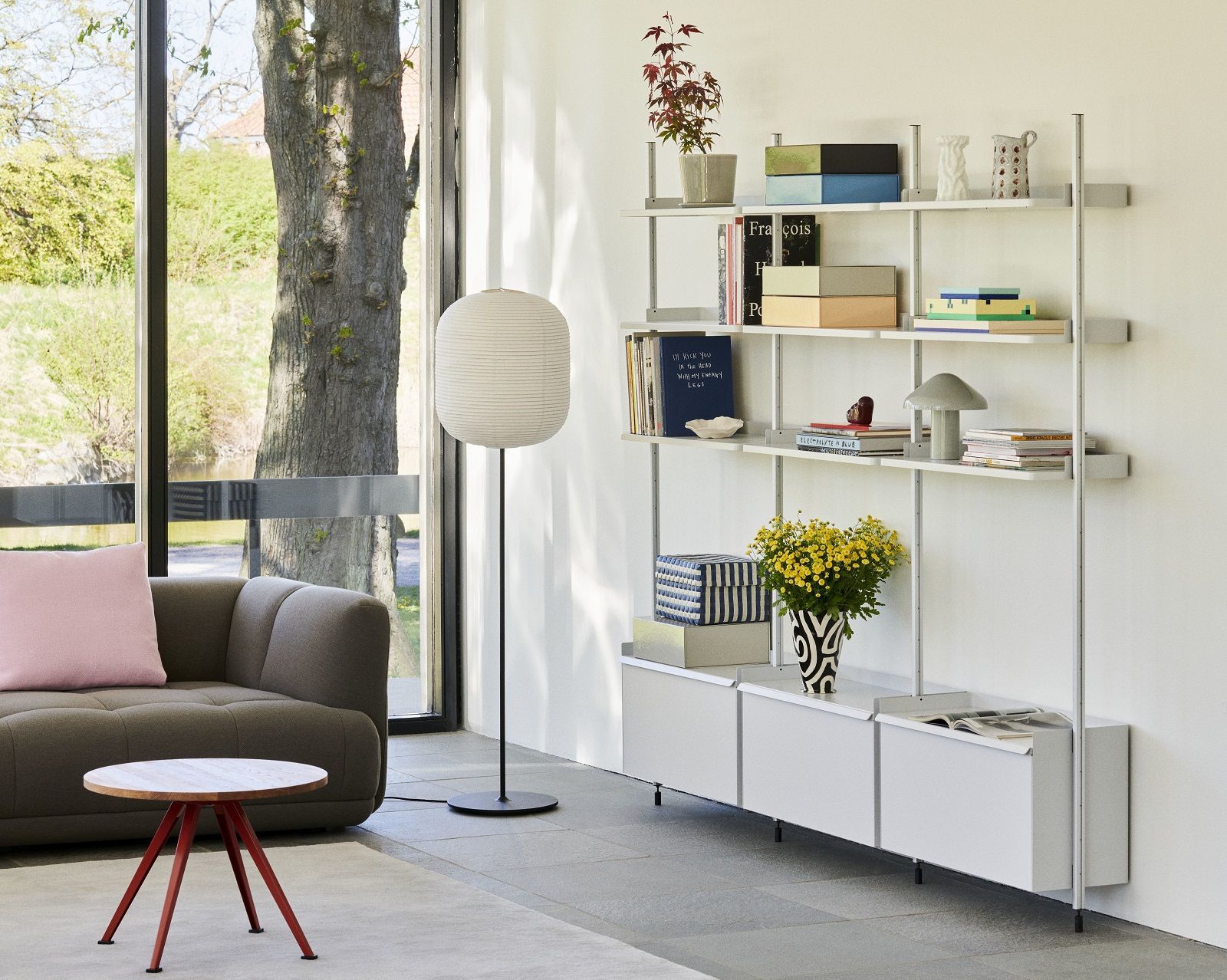 Helles Wohnzimmer mit HAY Pier System Regal, weißem Regal mit drei Säulen und Dekoration.