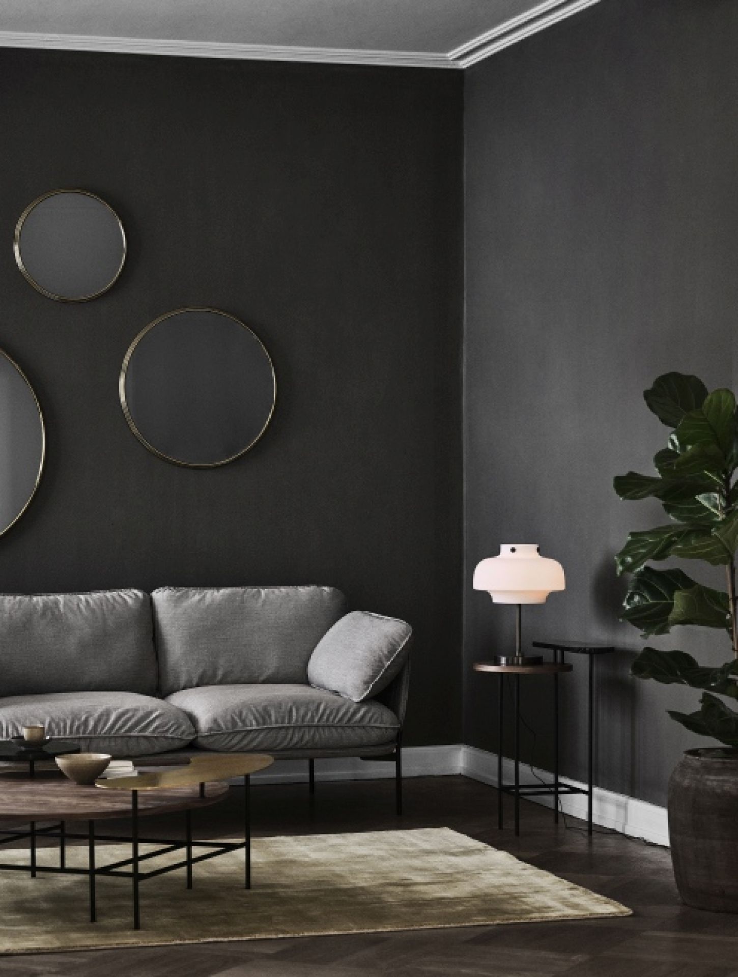 Wohnzimmer mit grauem Sofa, runden Spiegeln und AndTradition Palette Table JH25 Couchtisch aus Holz und Metall.