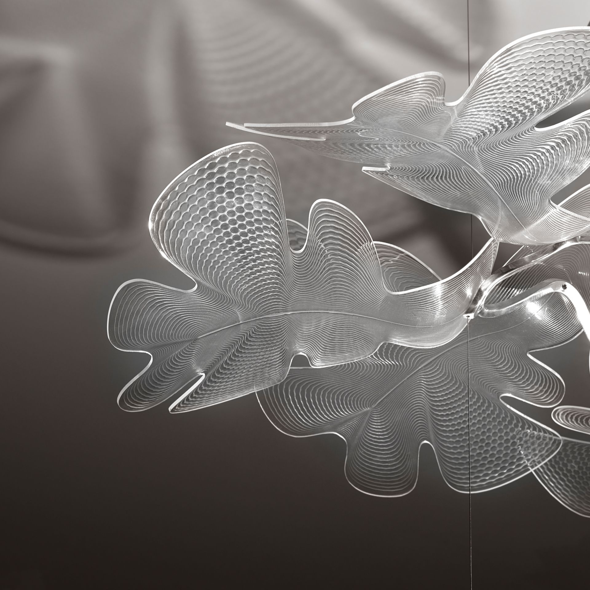 Detailaufnahme der Artemide Chlorophilia Pendelleuchte mit transparentem Diffusor und Chromstruktur. Designlampe für moderne Innenräume.