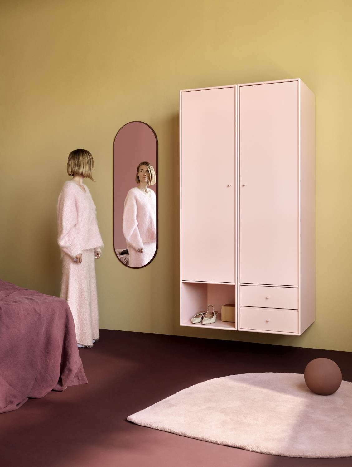 Frau betrachtet sich im Colour Frame Spiegel (Montana Oyster) in einem stilvollen Interieur.