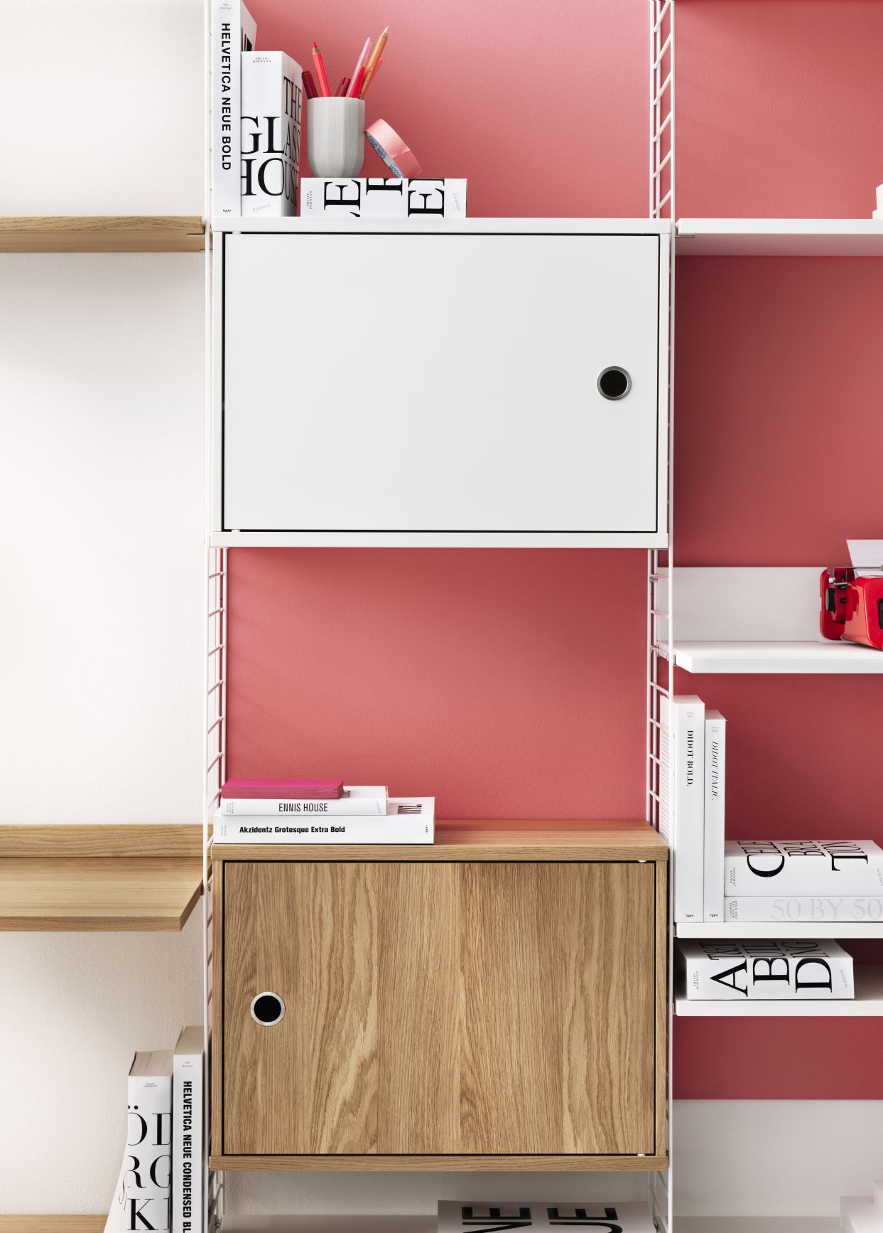 Detailaufnahme: String Furniture Schrankelement mit Walnuss-Schwenktür, Teil eines modularen Regalsystems.