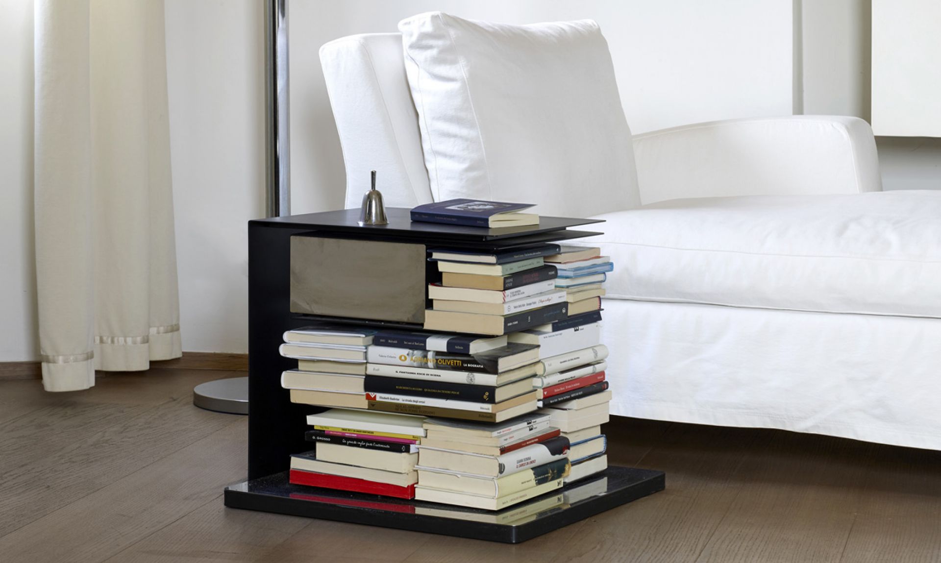 Ptolomeo Bücherregal: Schwarze Bücher-Säule mit vielen Büchern als dekoratives Möbelstück im Wohnzimmer.