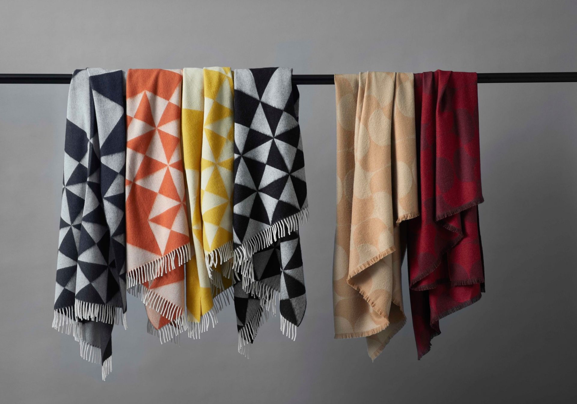 Mehrere Verpan Mirror Throw Überwürfe in verschiedenen Farben und Mustern hängen an einer Stange.