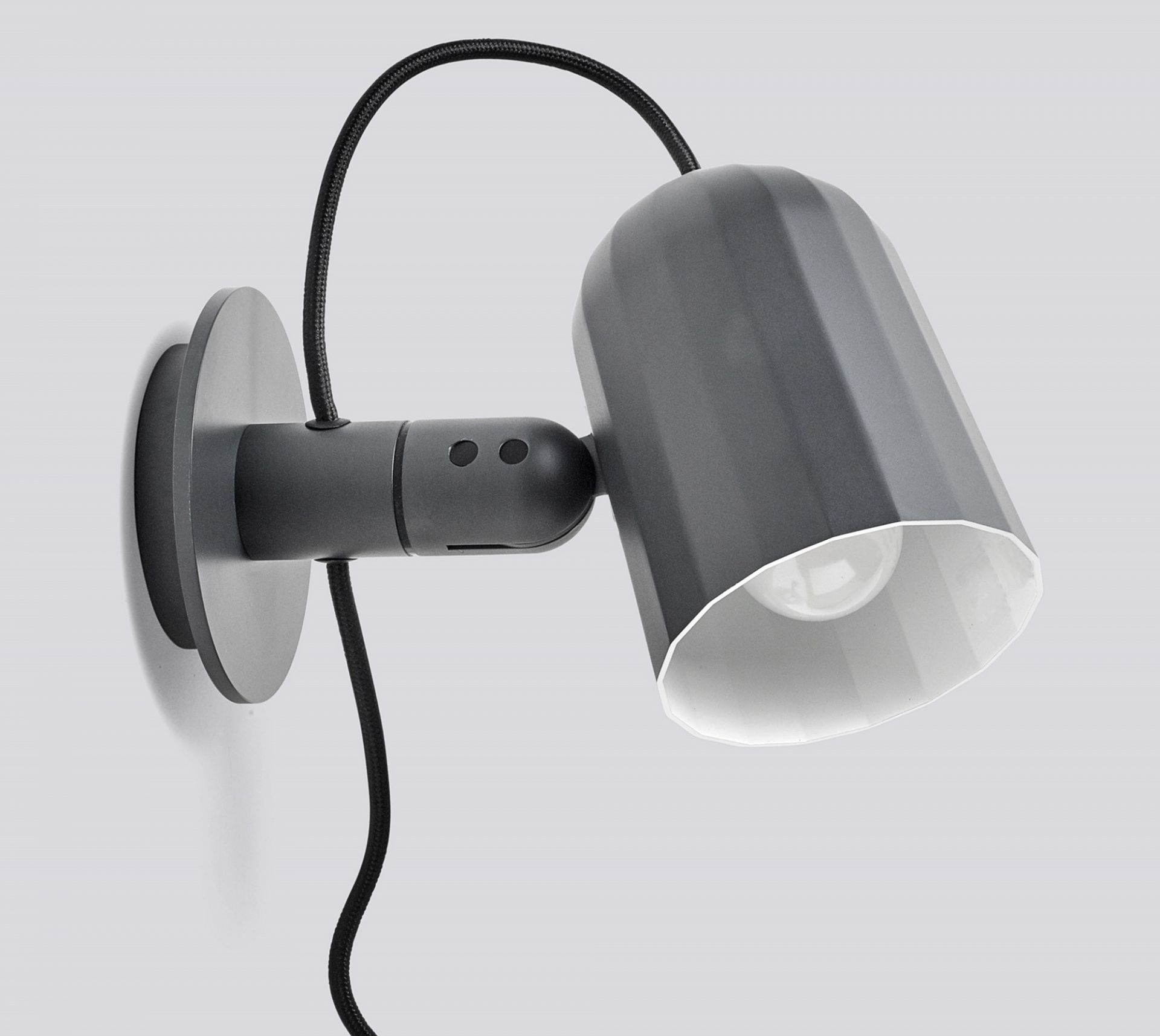 Nahaufnahme der grauen Noc Wall Wandleuchte von Hay mit schwarzem Kabel und weißem Lampenschirm.