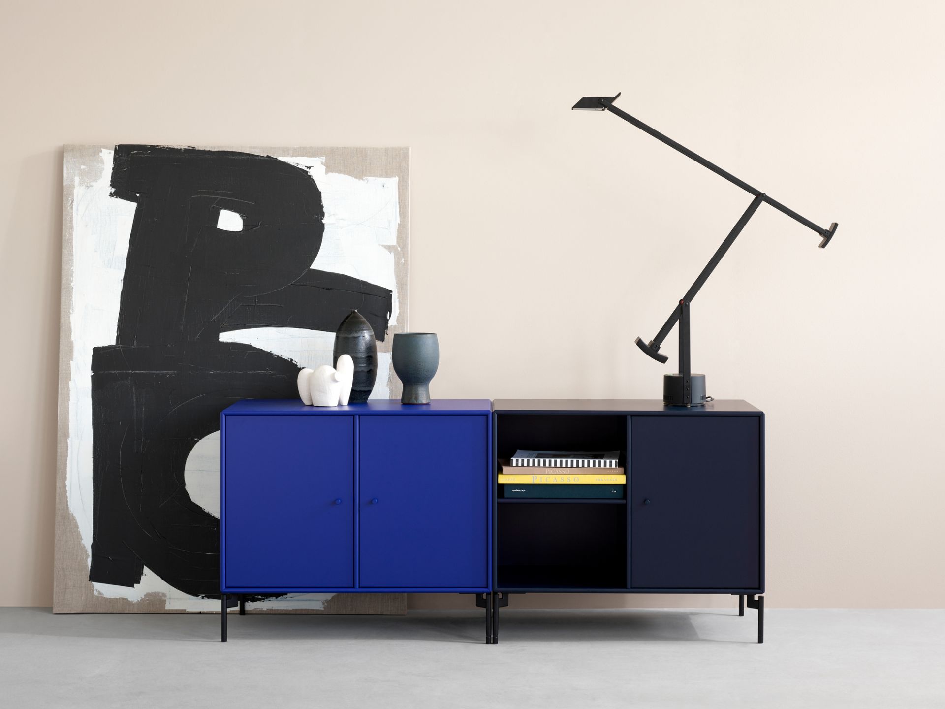 Blaues Montana Save Sideboard Low A mit schwarzen Füßen und Lampe im modernen Wohnraum.