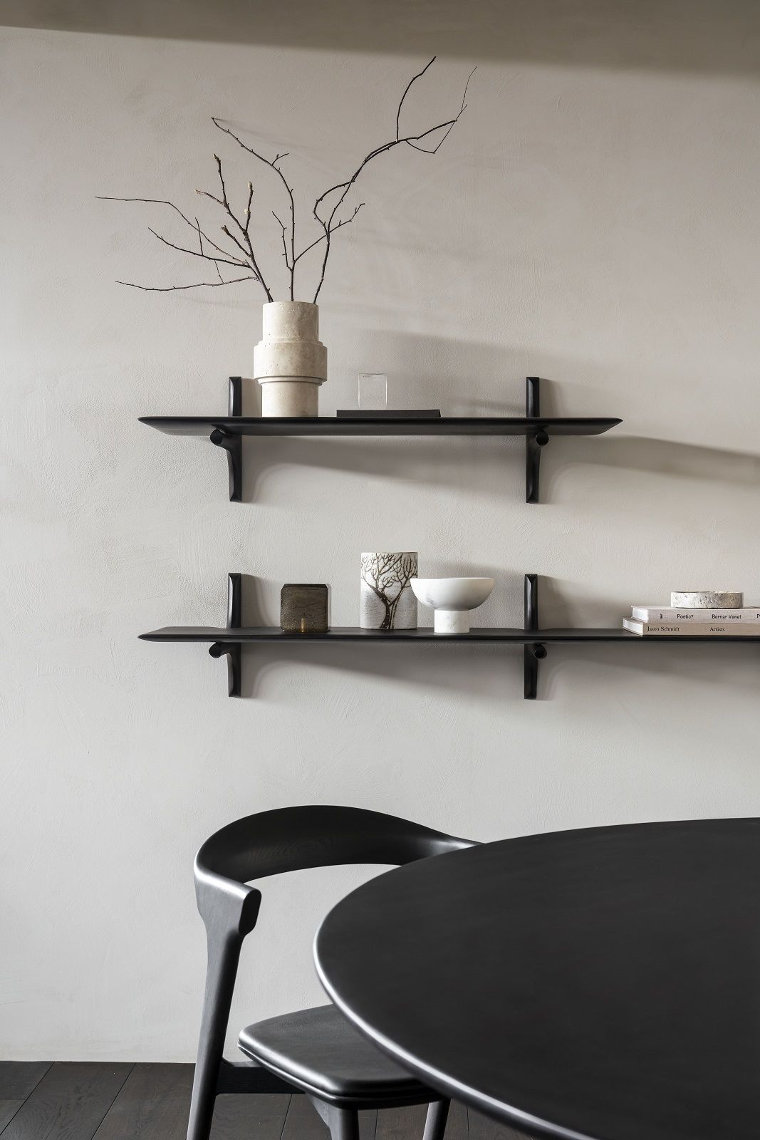 Zwei dunkle PI Wandregale von Ethnicraft mit Dekoartikeln an einer hellen Wand.