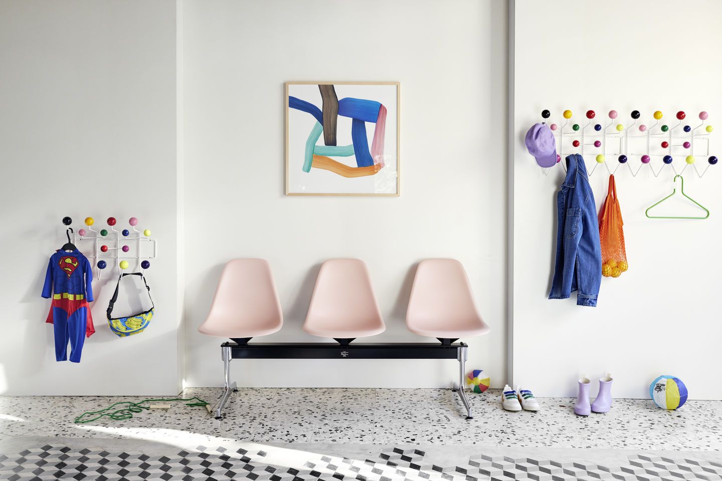 Drei rosa Eames Plastic Side Chairs auf Traverse Vitra im Wartebereich mit Garderobe.
