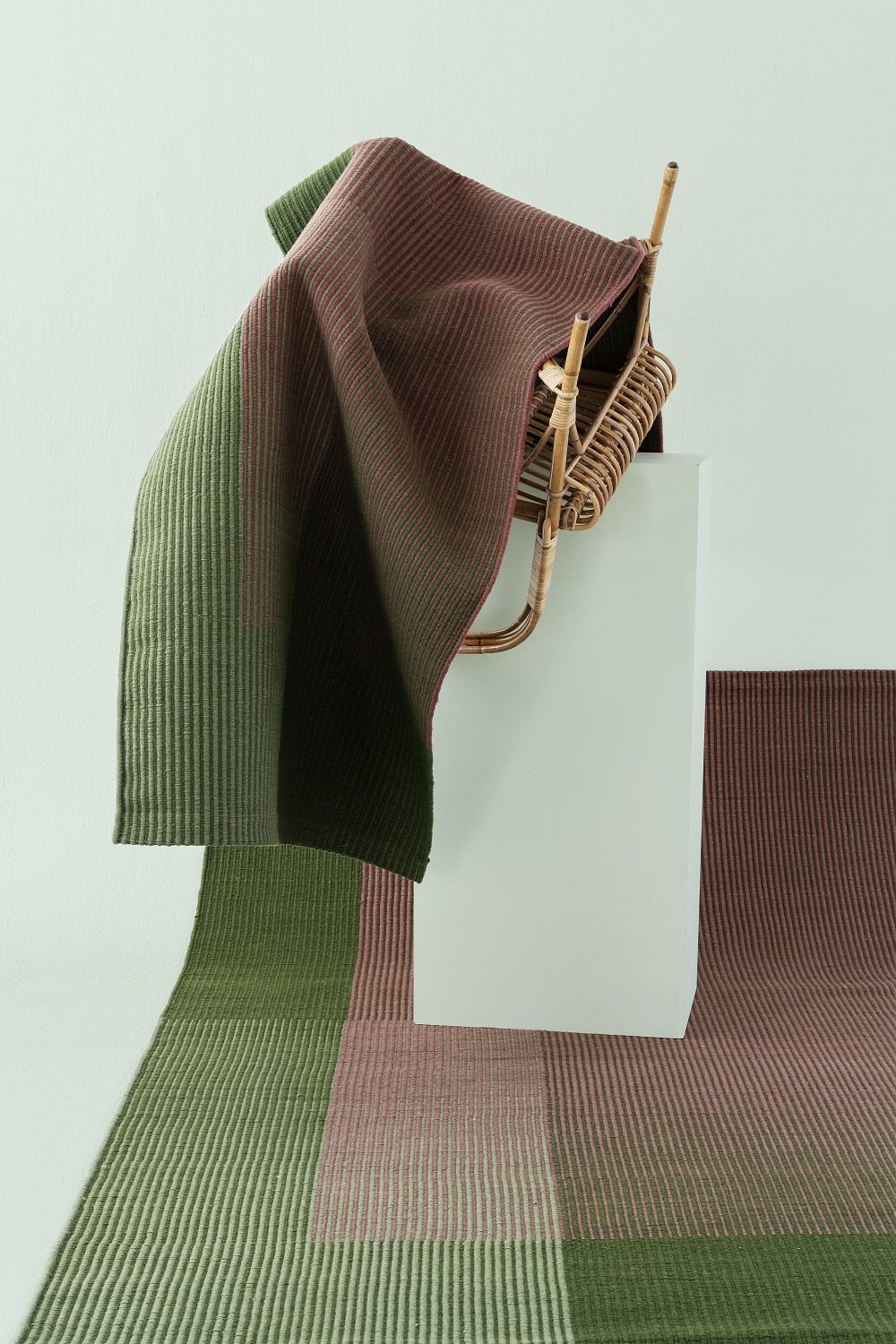 Haze Runner Teppich von Nanimarquina in Grün- und Brauntönen auf einem kleinen Stuhl.